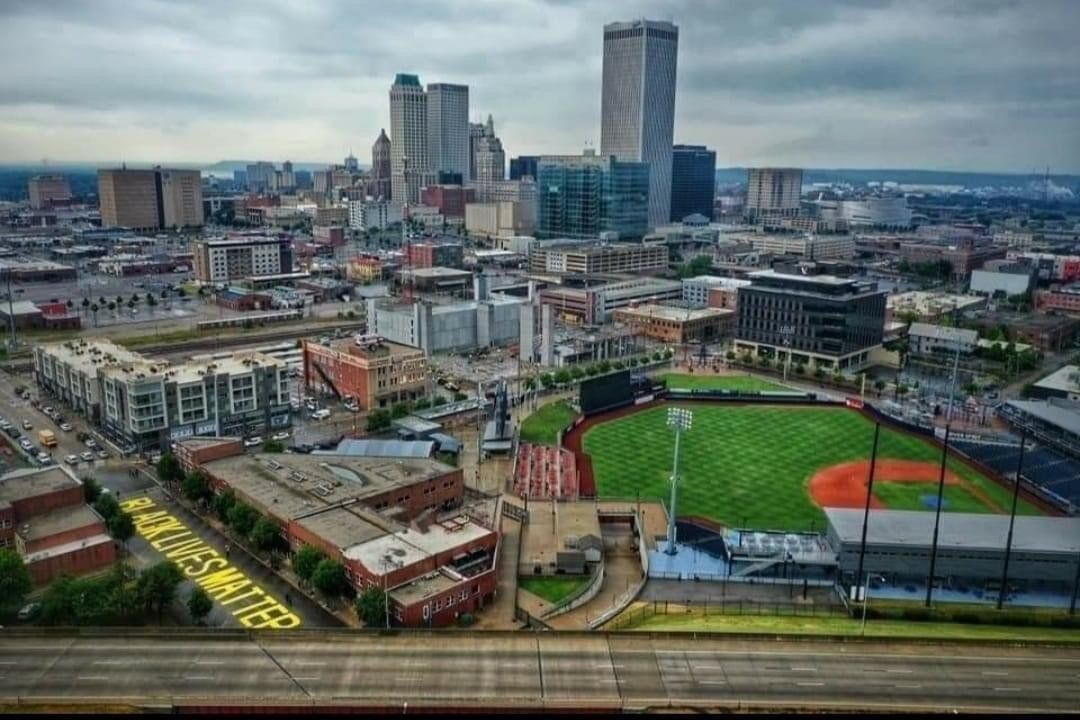 An aerial view of a city with a baseball field in the foreground
