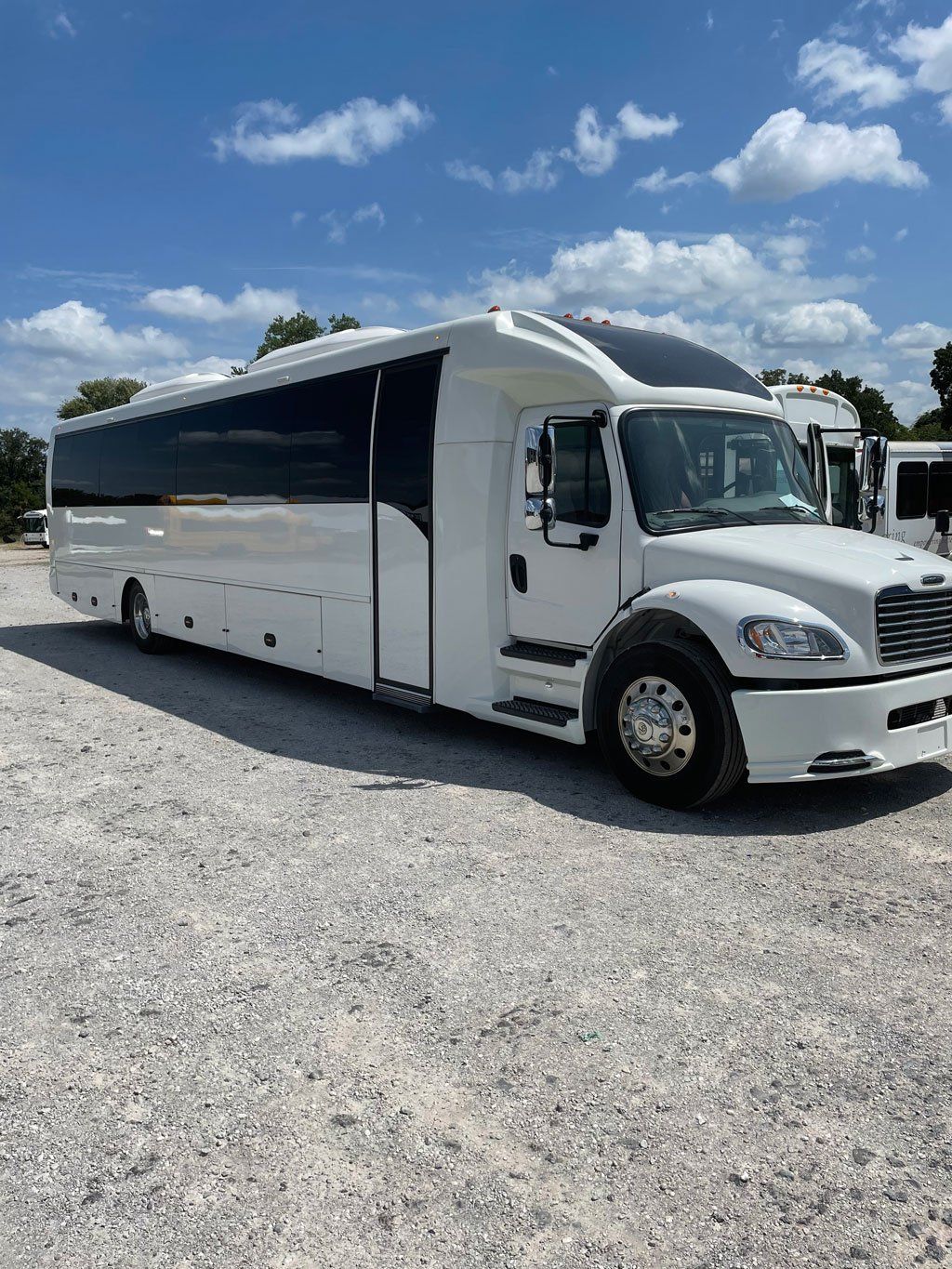 A large white bus is parked in a gravel lot.