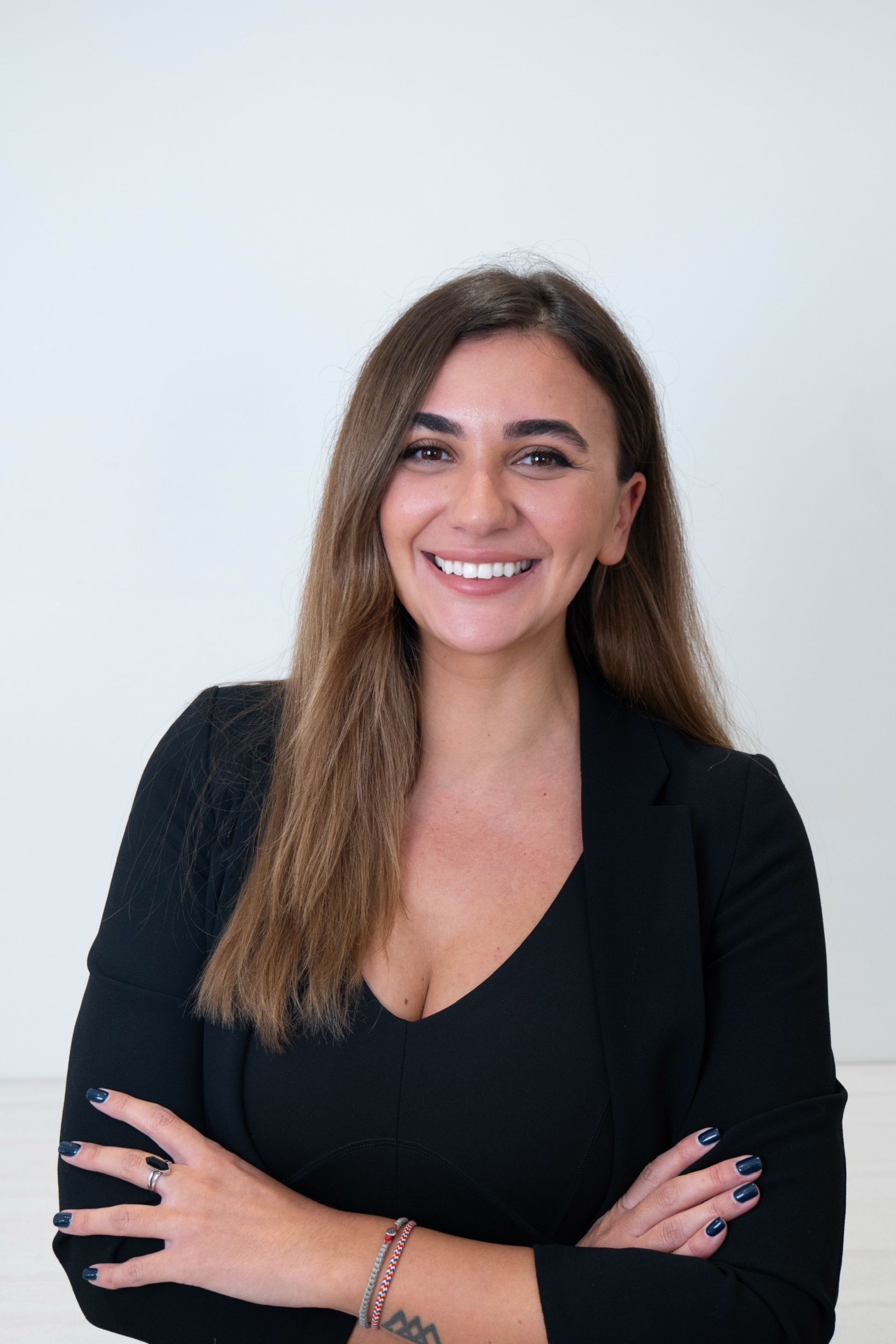 A woman in a black shirt is smiling with her arms crossed.