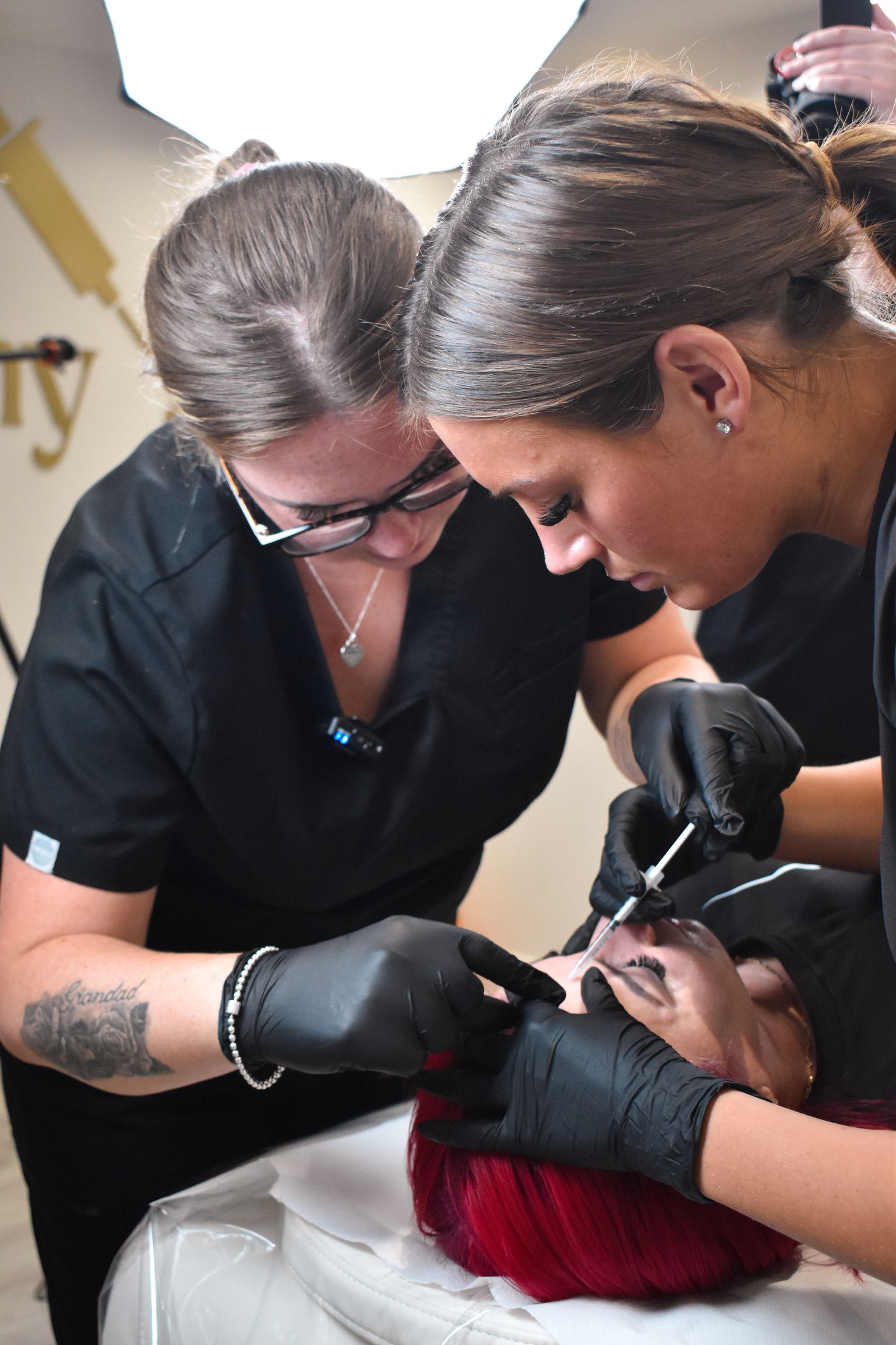 Two women are working on a person 's face in a beauty salon.