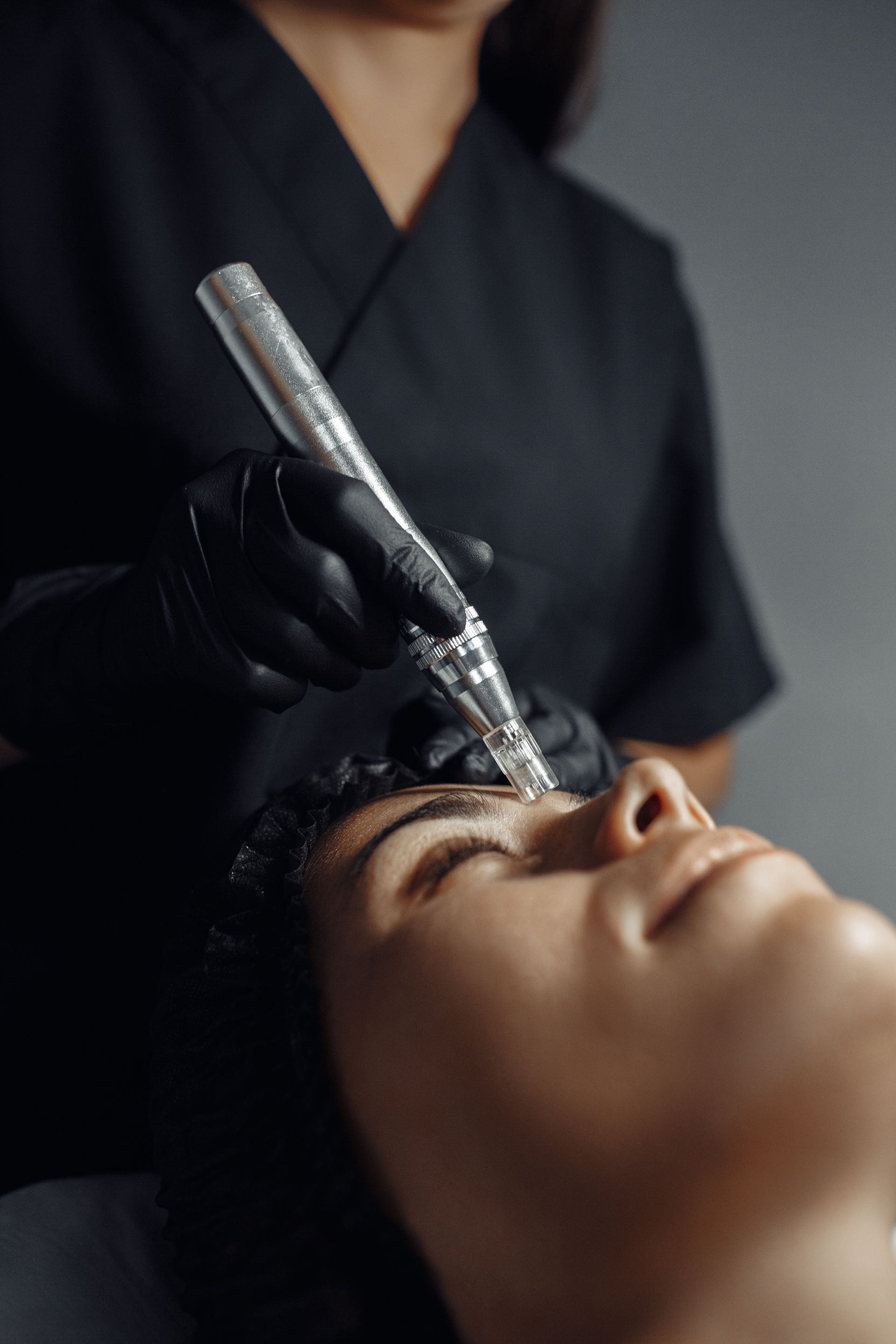 A woman is getting a tattoo on her eyebrows with a machine.