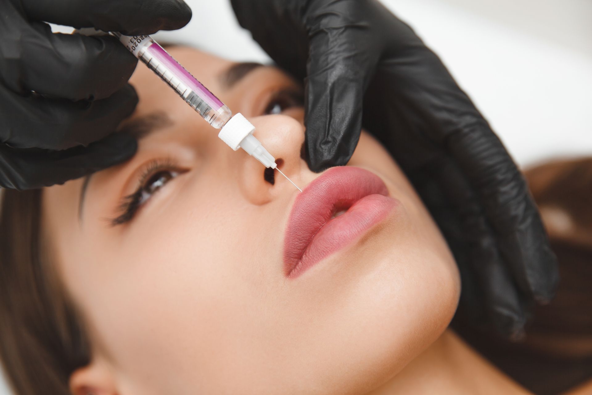 A woman is getting a botox injection in her nose.