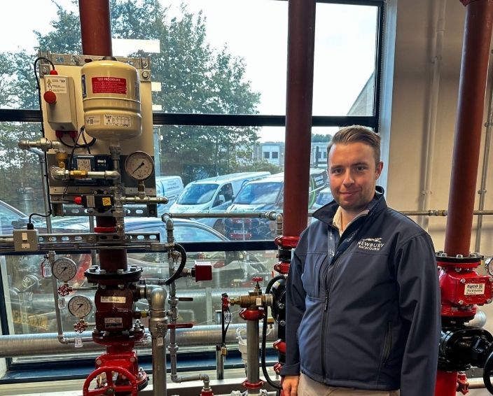 A man in a blue jacket is standing in front of a machine