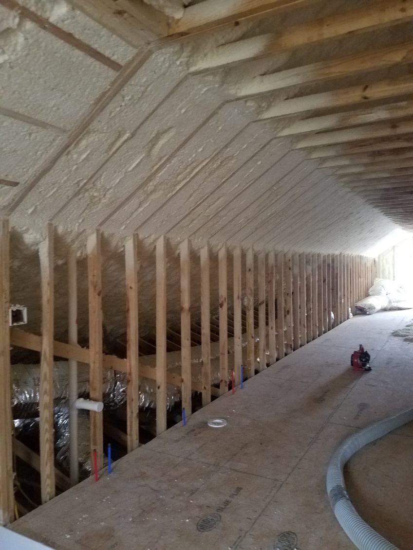 A room with light wood paneling, exposed structural beams, and large windows with a view of trees outside.