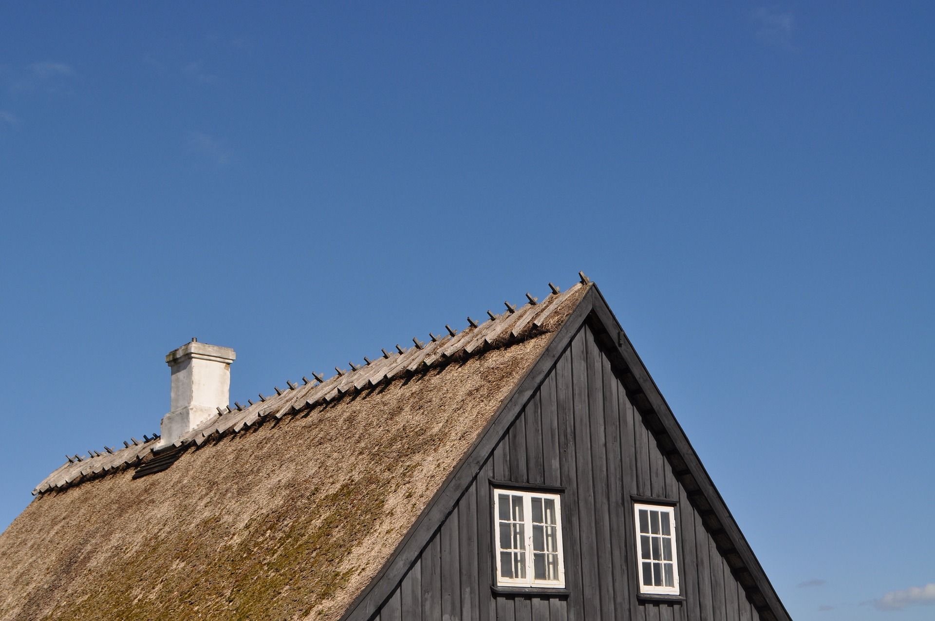 A House With A Thatched Roof And A Chimney