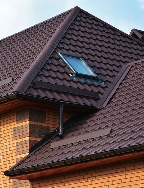 A Brick House With A Brown Roof And A Skylight