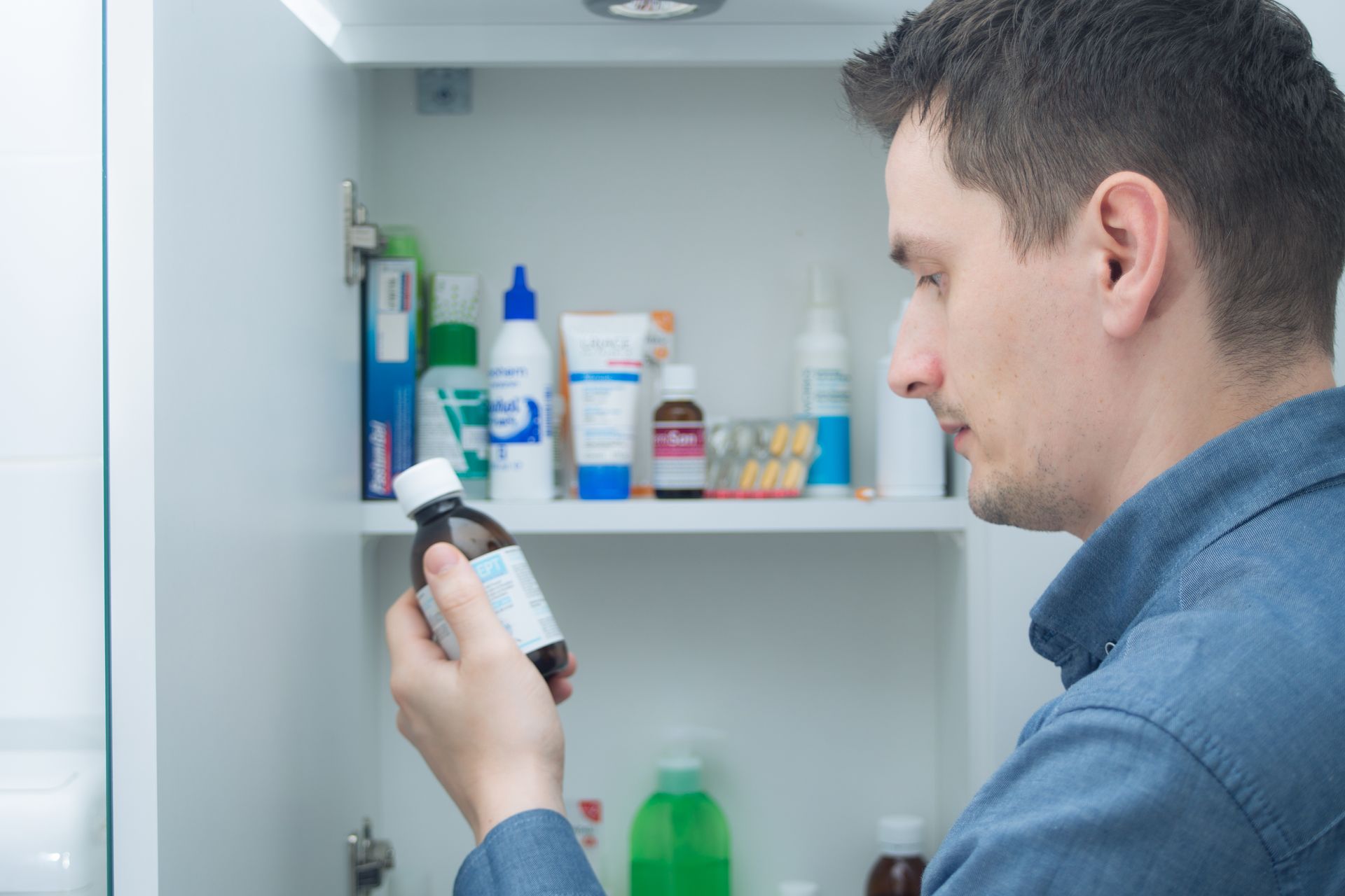 male cleaning out medicine cabinet