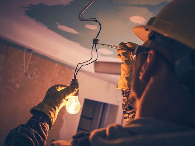 A man is testing a light bulb in a room.