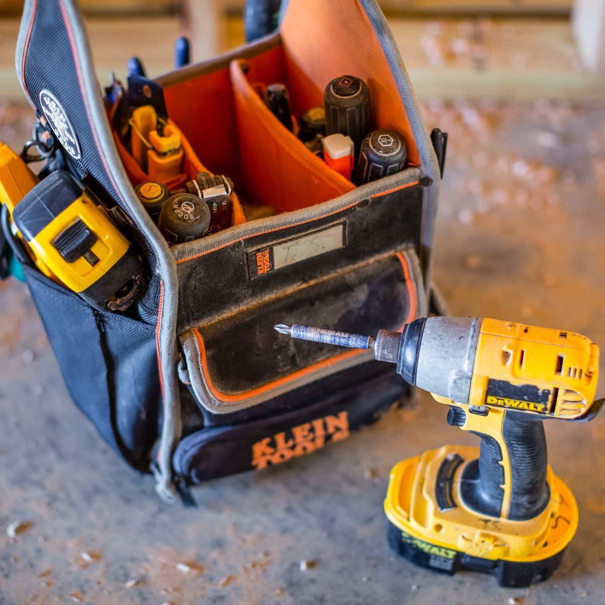 A klein tool bag filled with tools and a drill