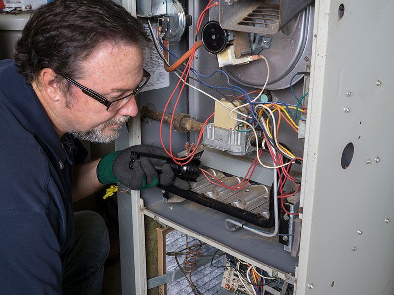 A man is working on a heating system with a wrench.