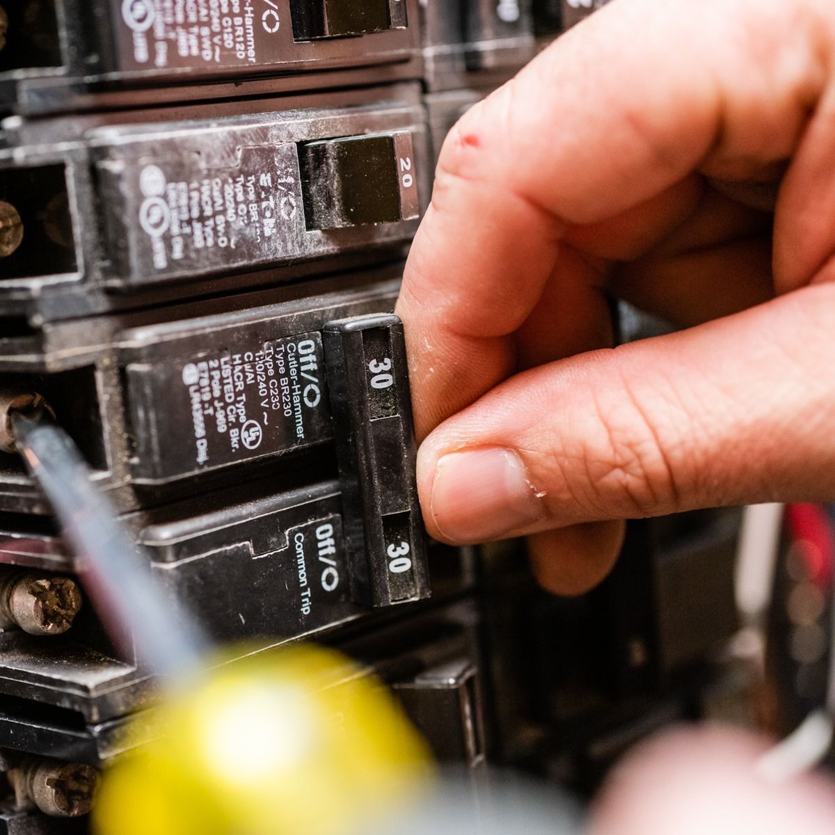 A person is working on a circuit breaker with a screwdriver