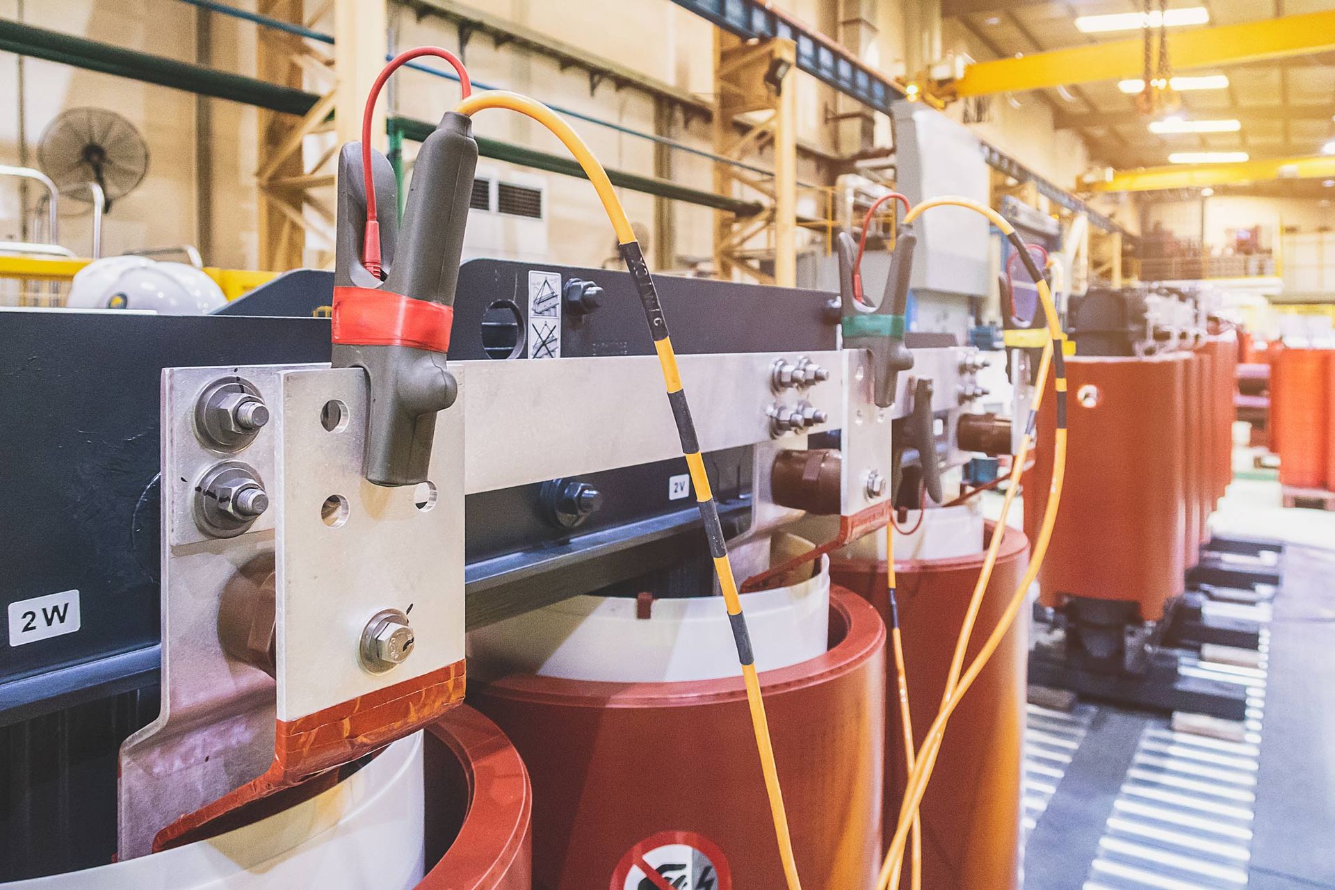 A row of transformers are lined up in a factory.