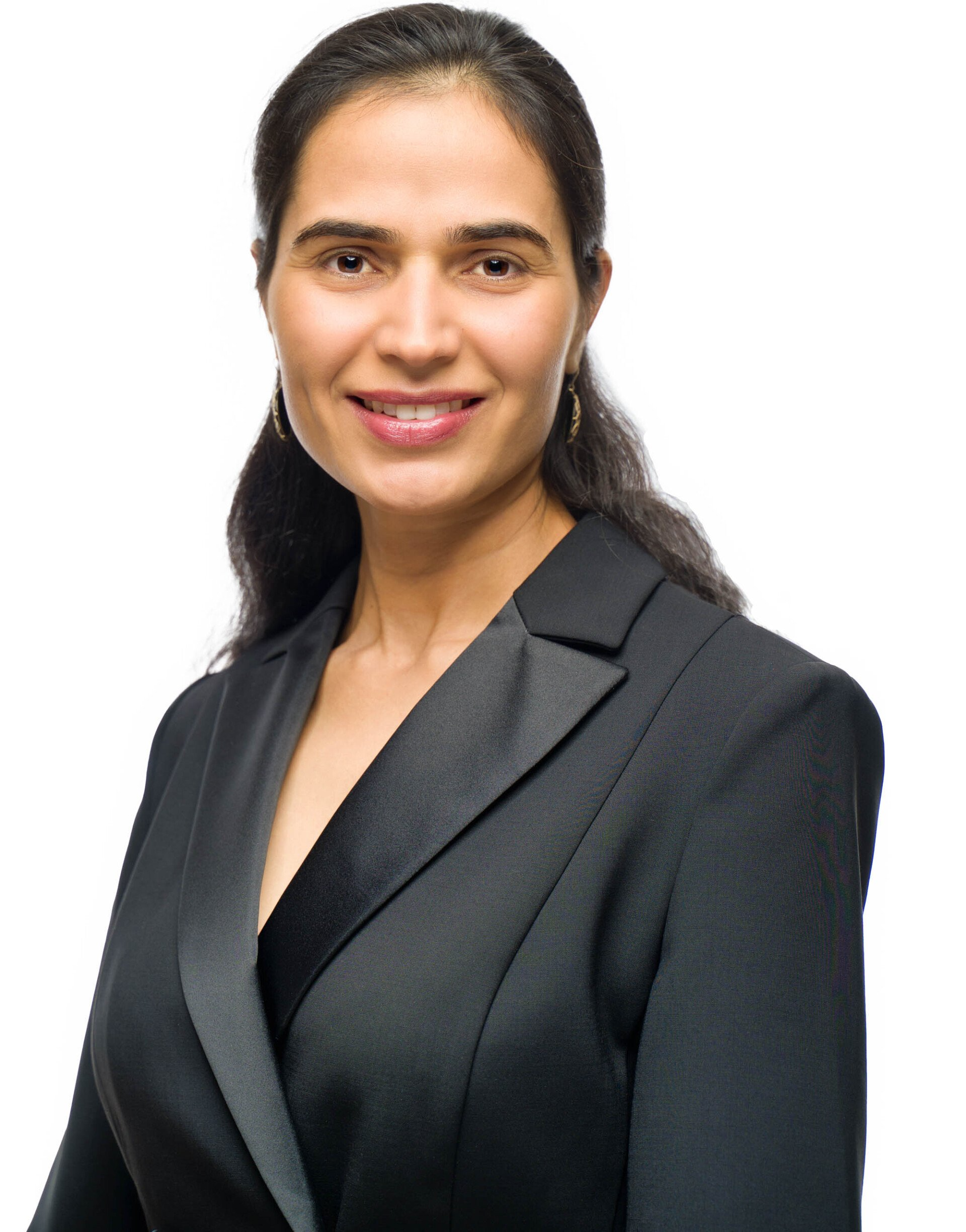 Woman in black blazer smiles, looking at camera.