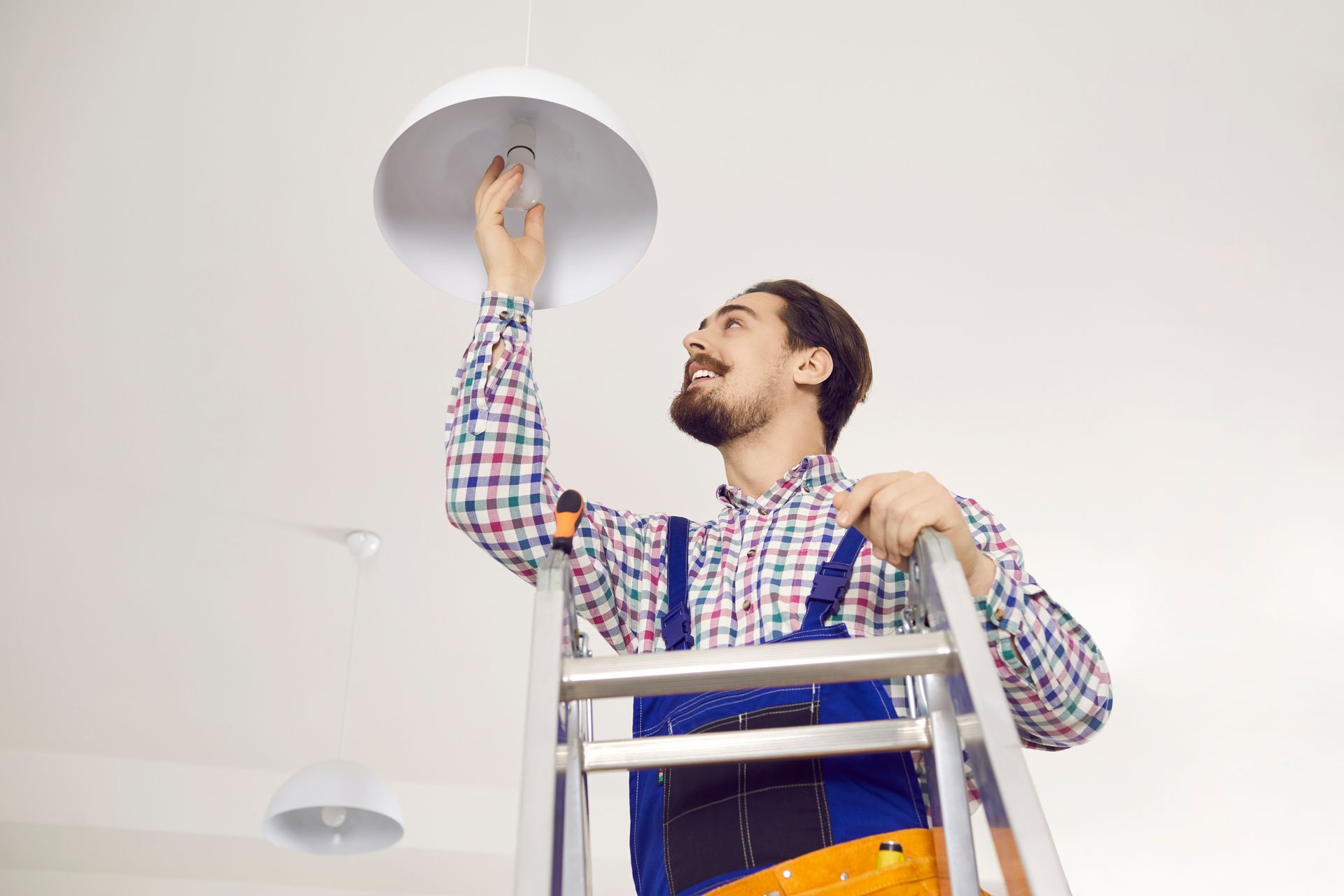 Technician inside a modern apartment installing an LED ceiling lamp.