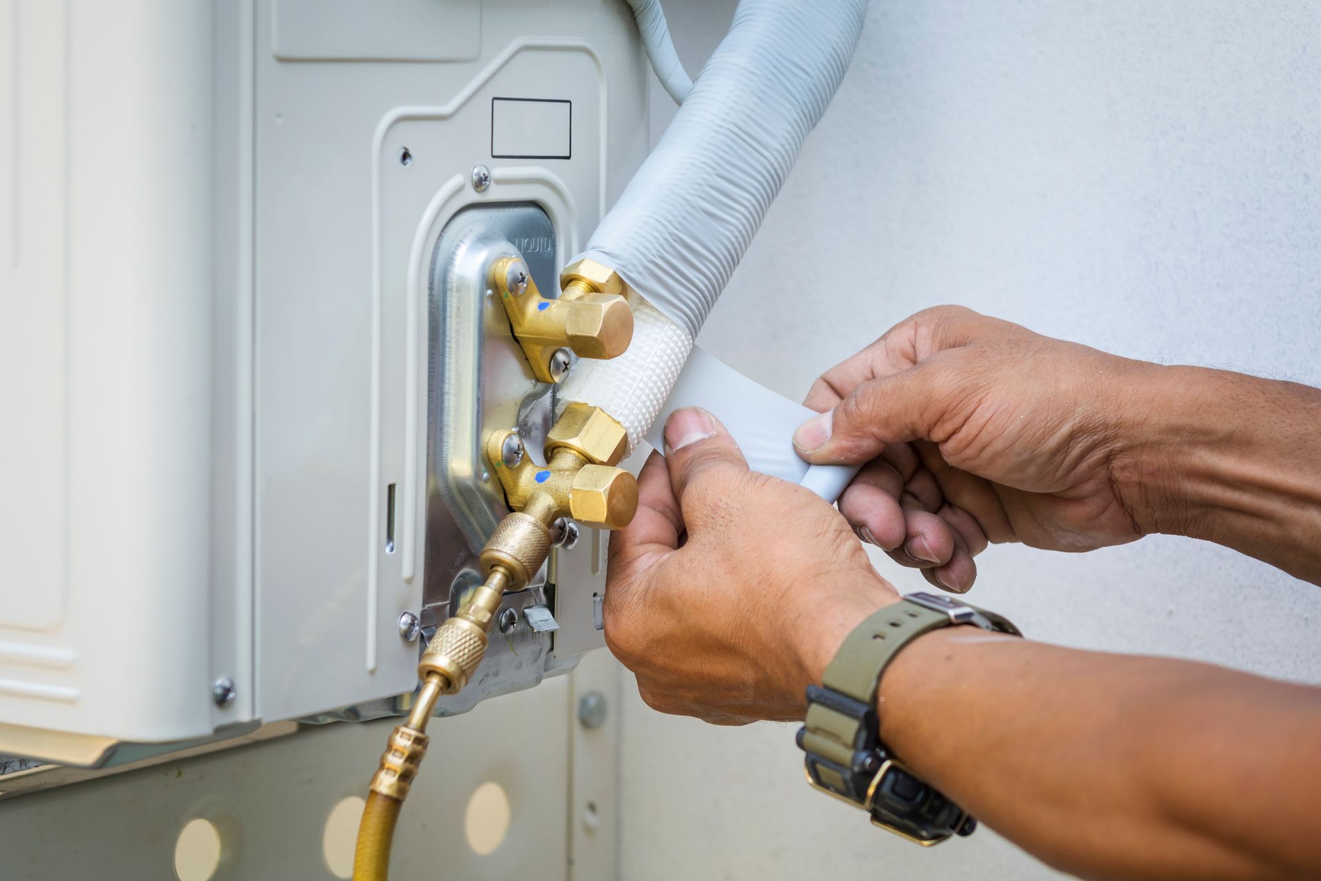 Technician carrying out HVAC installation on a wall-mounted air conditioner unit.