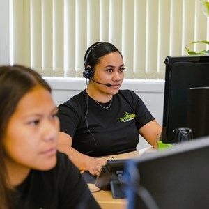 A woman wearing a headset is sitting in front of a computer.