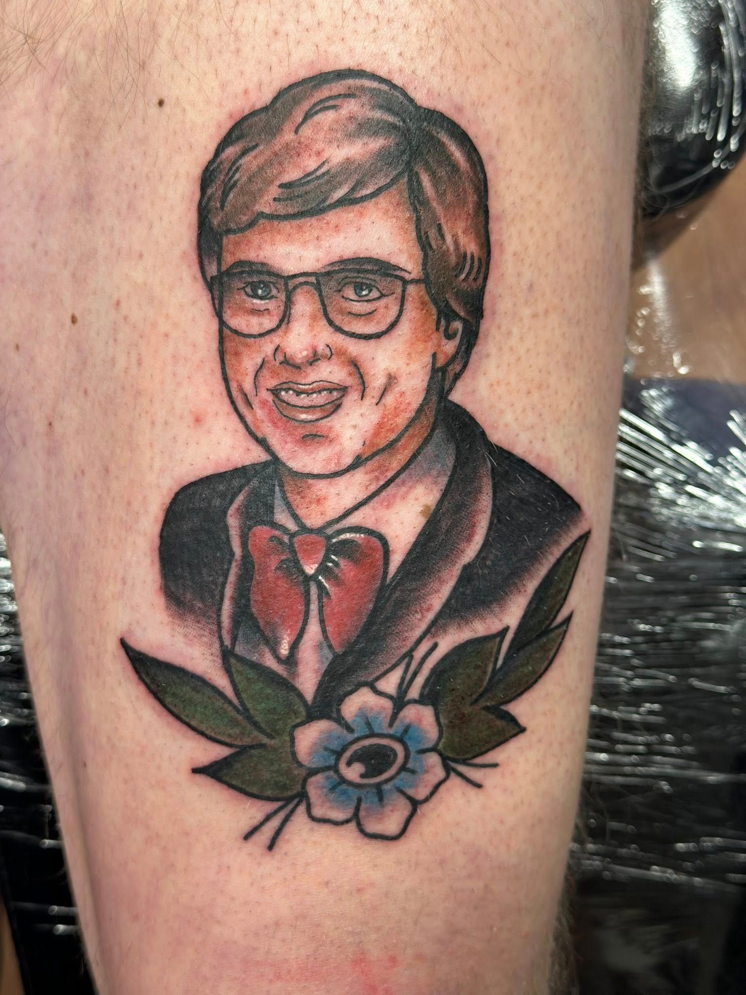 Farget portrett-tatovering av mann med briller, rød sløyfe og blomster – tradisjonell stil