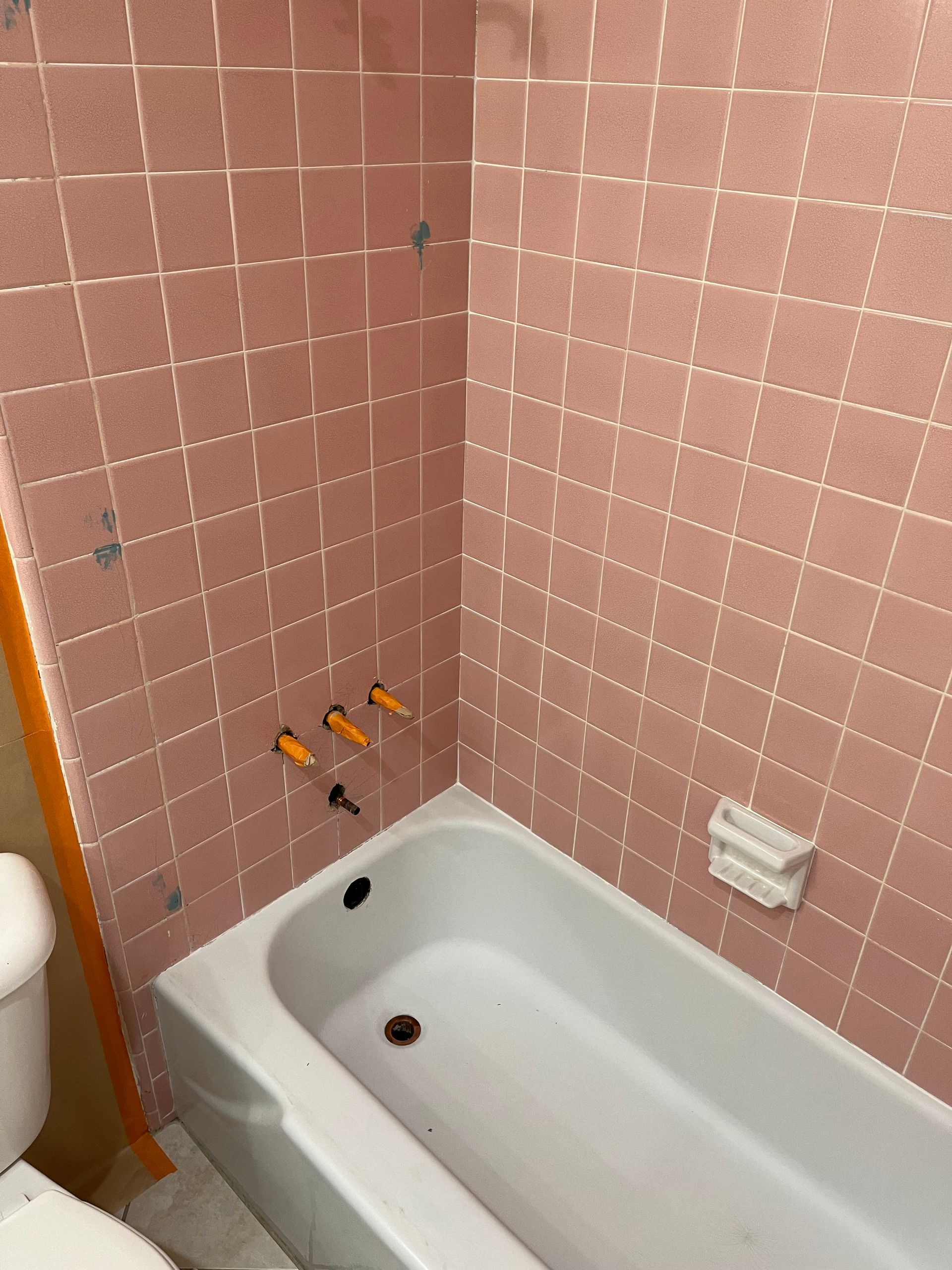 A bathroom with pink tiles and a bathtub