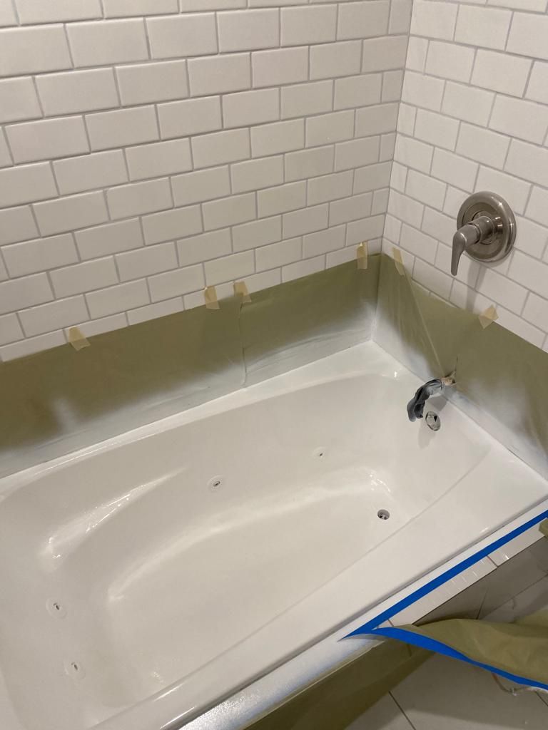 a bathtub is being painted in a bathroom with white brick walls .