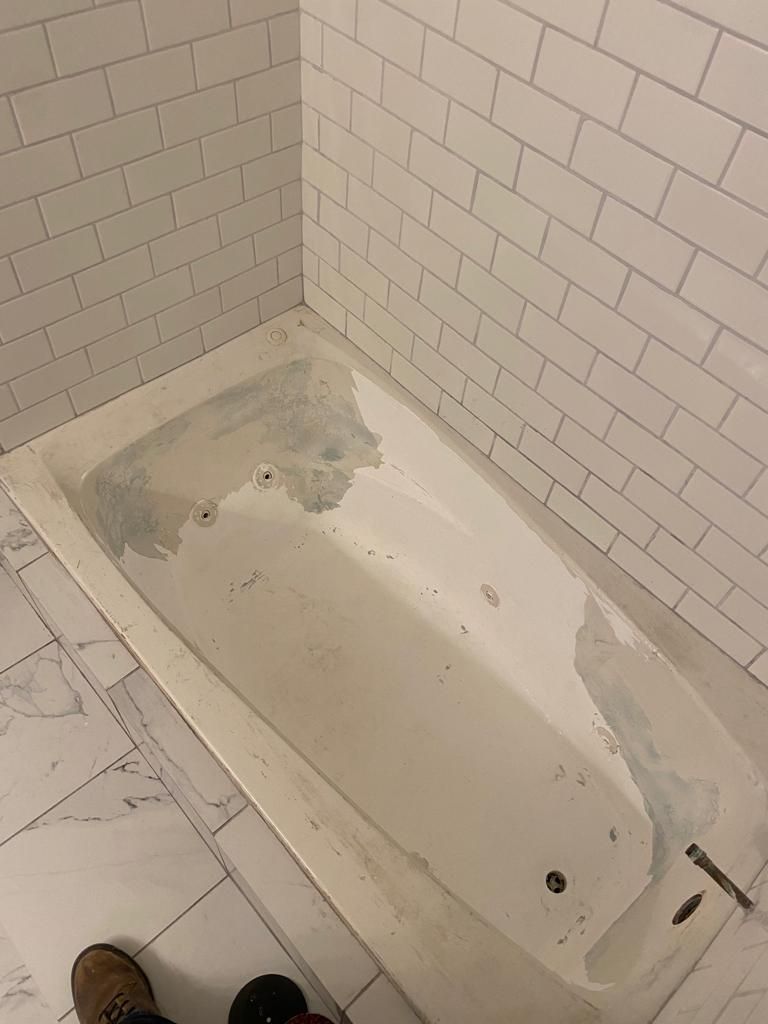 a bathtub is sitting in a corner of a bathroom next to a white brick wall .