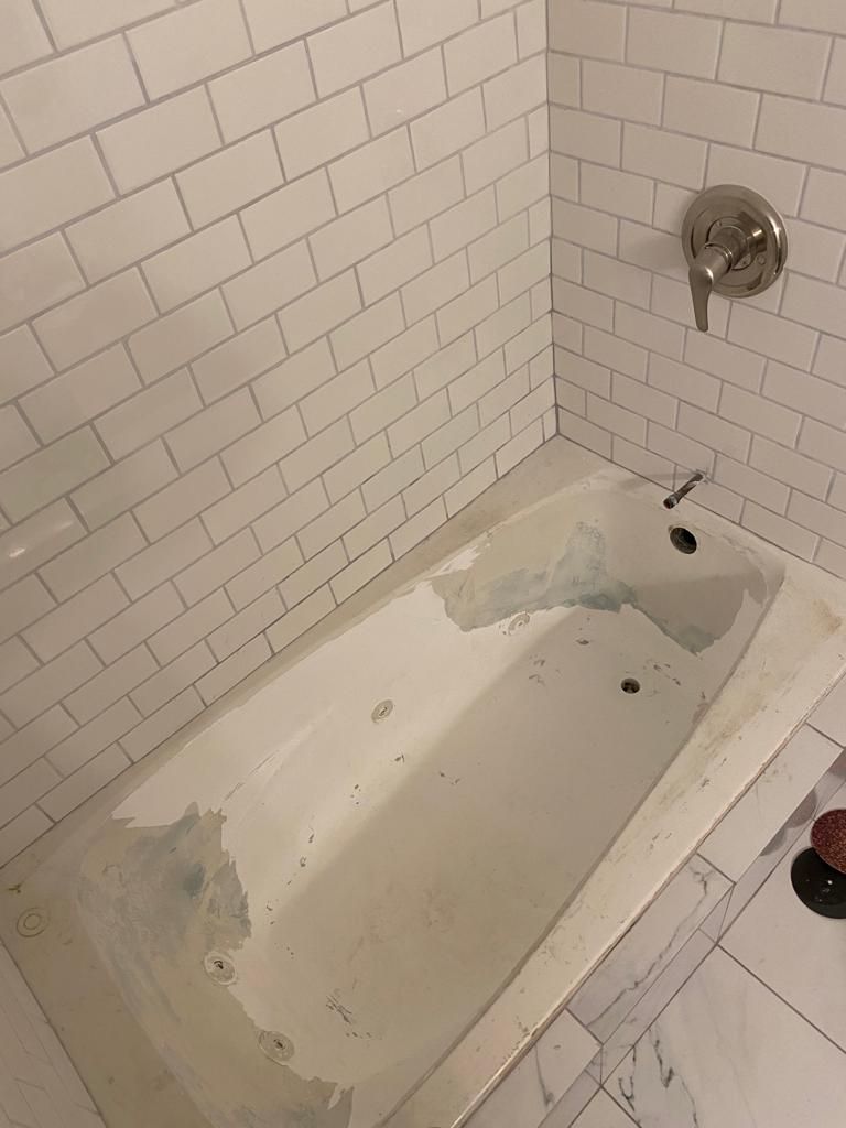 a bathtub is sitting in a corner of a bathroom next to a white brick wall .