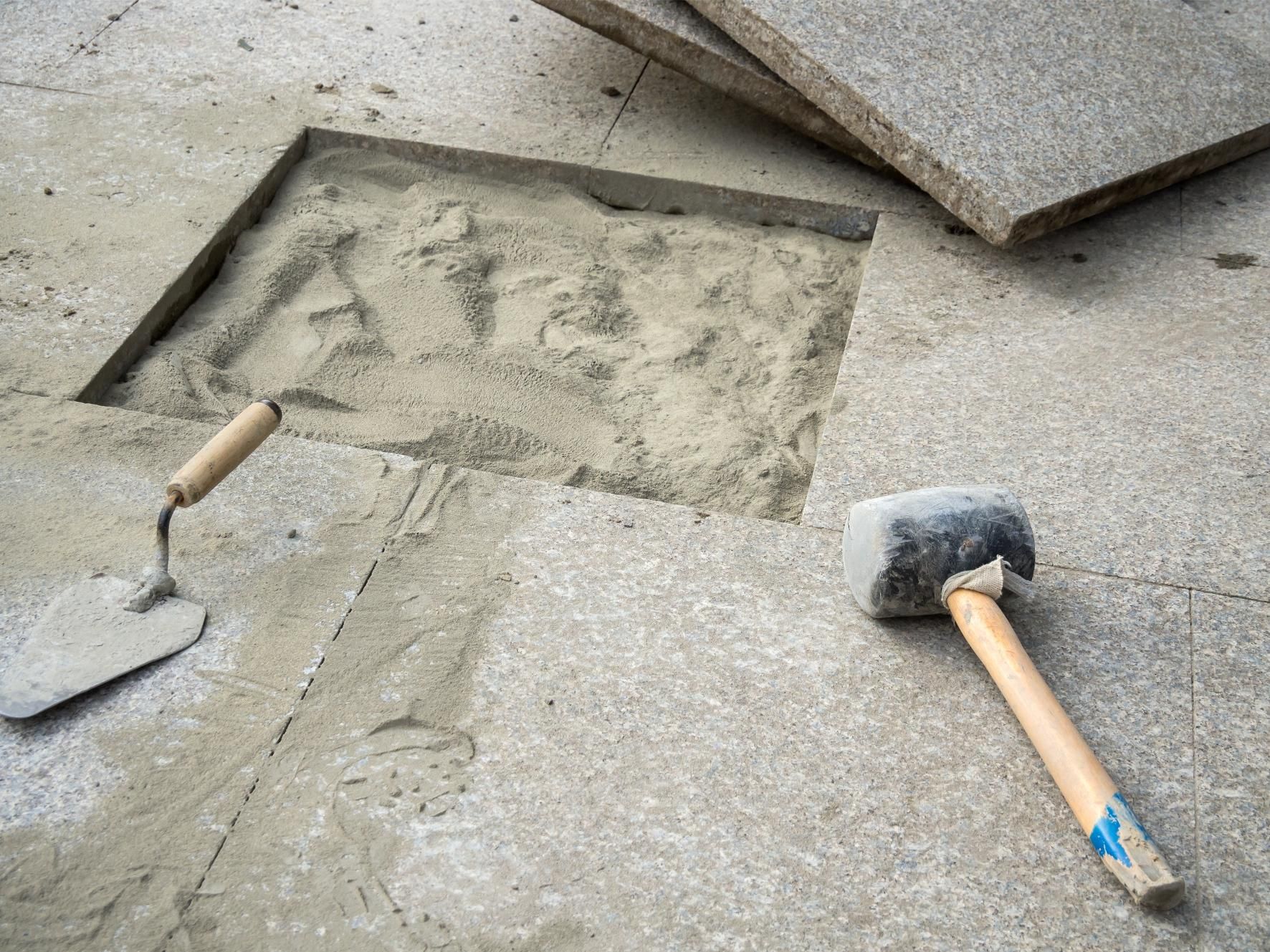a trowel and a rubber mallet are laying on a concrete floor .