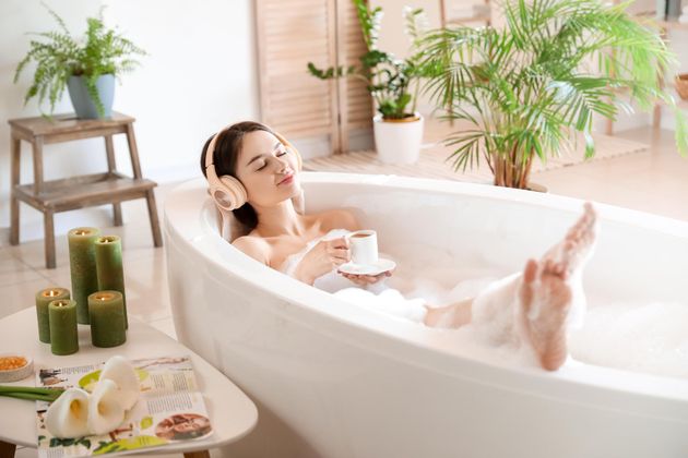 a woman is taking a bath in a bathtub with a cup of coffee .