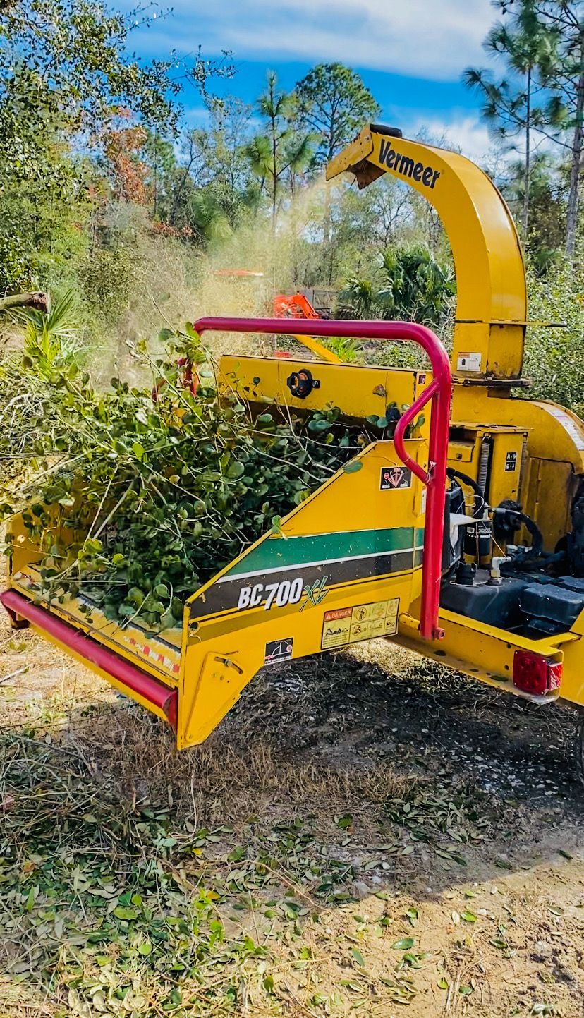 A yellow chipper is cutting trees in a forest.