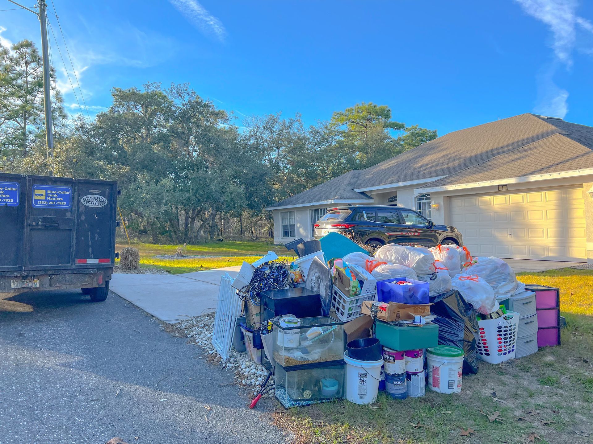 A dumpster is full of trash in front of a house.