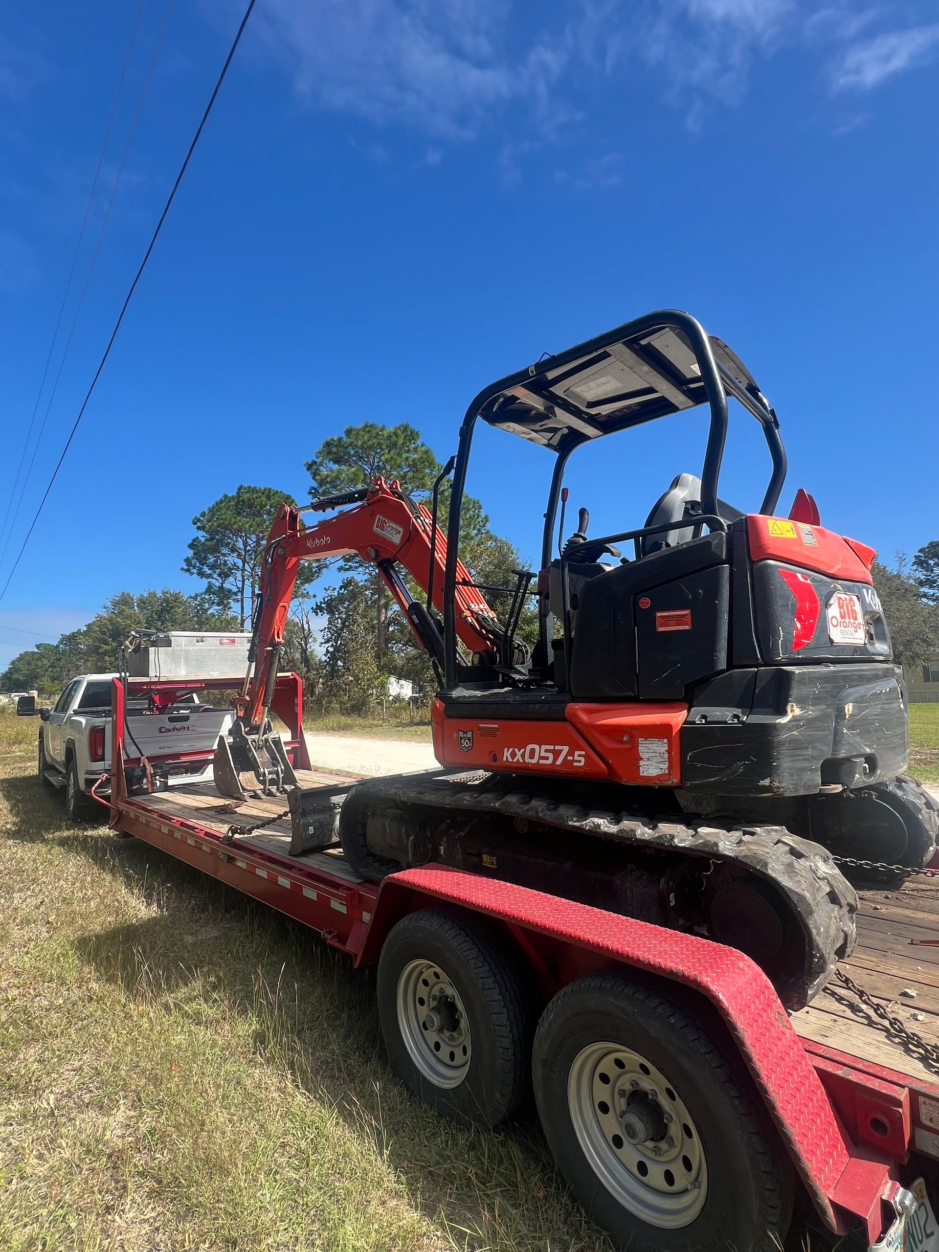 An excavator is sitting on top of a red trailer.