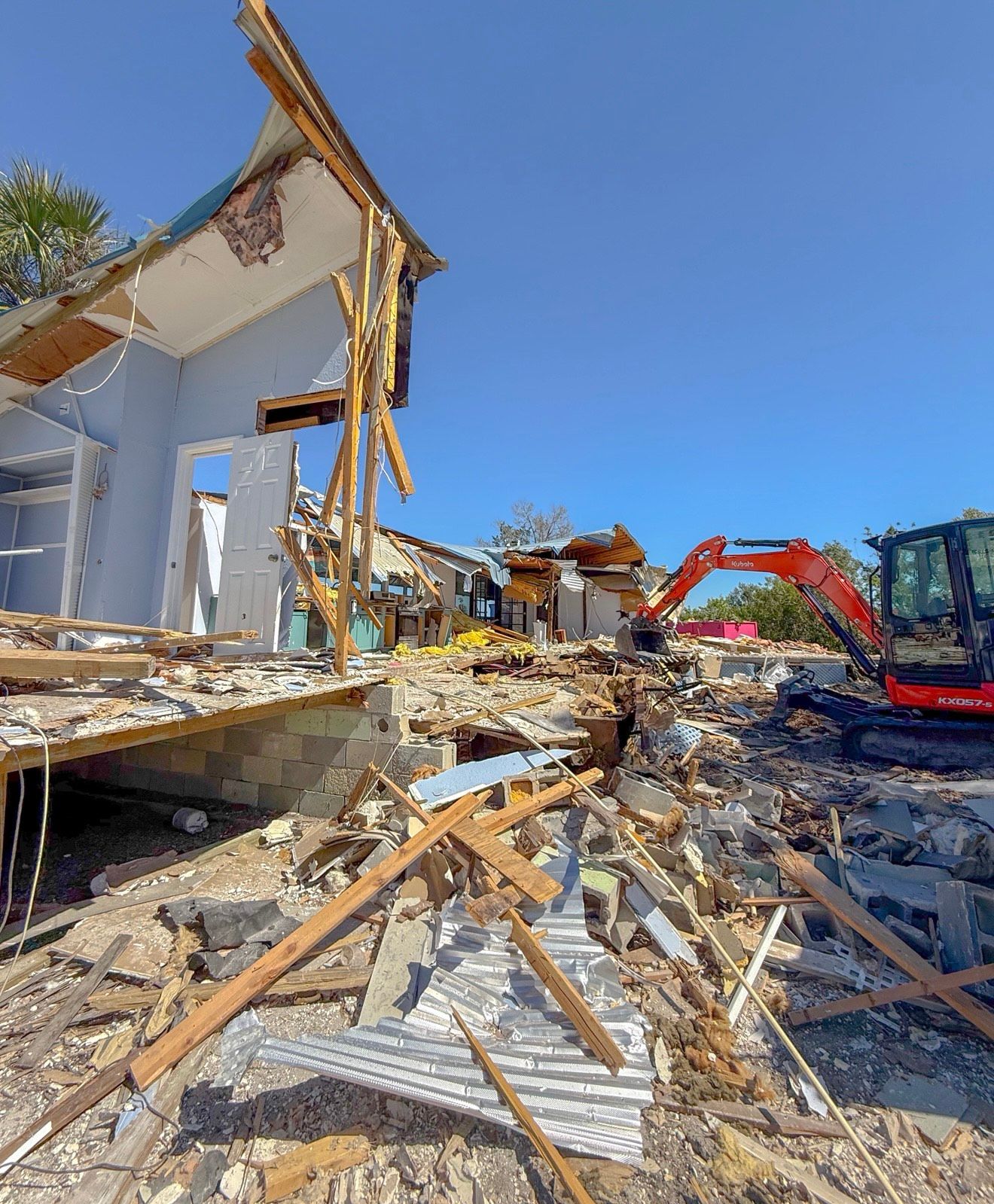 A man is driving a small excavator next to a shed.