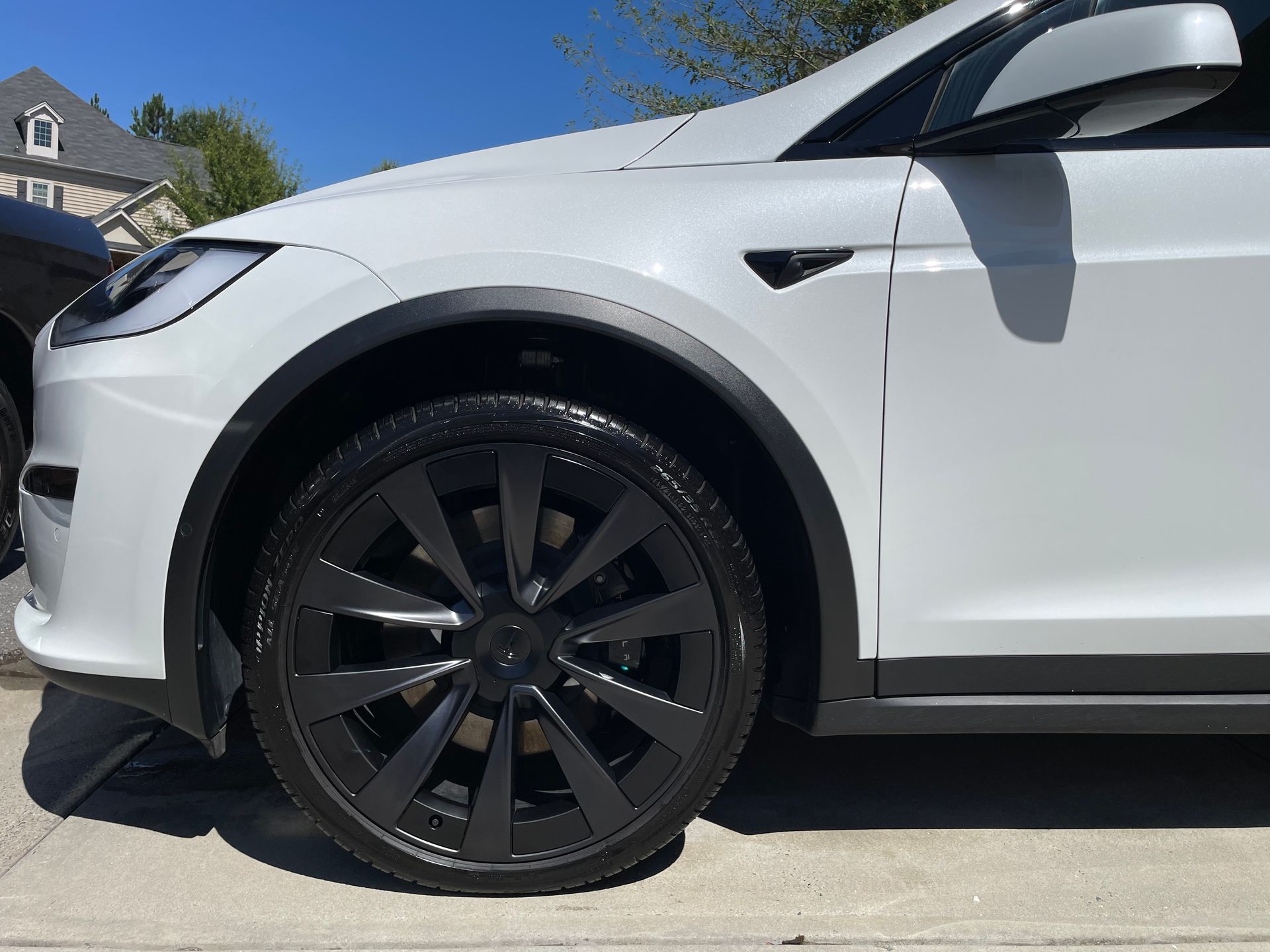 White SUV covered in foam at a car wash. A red car is in the background.