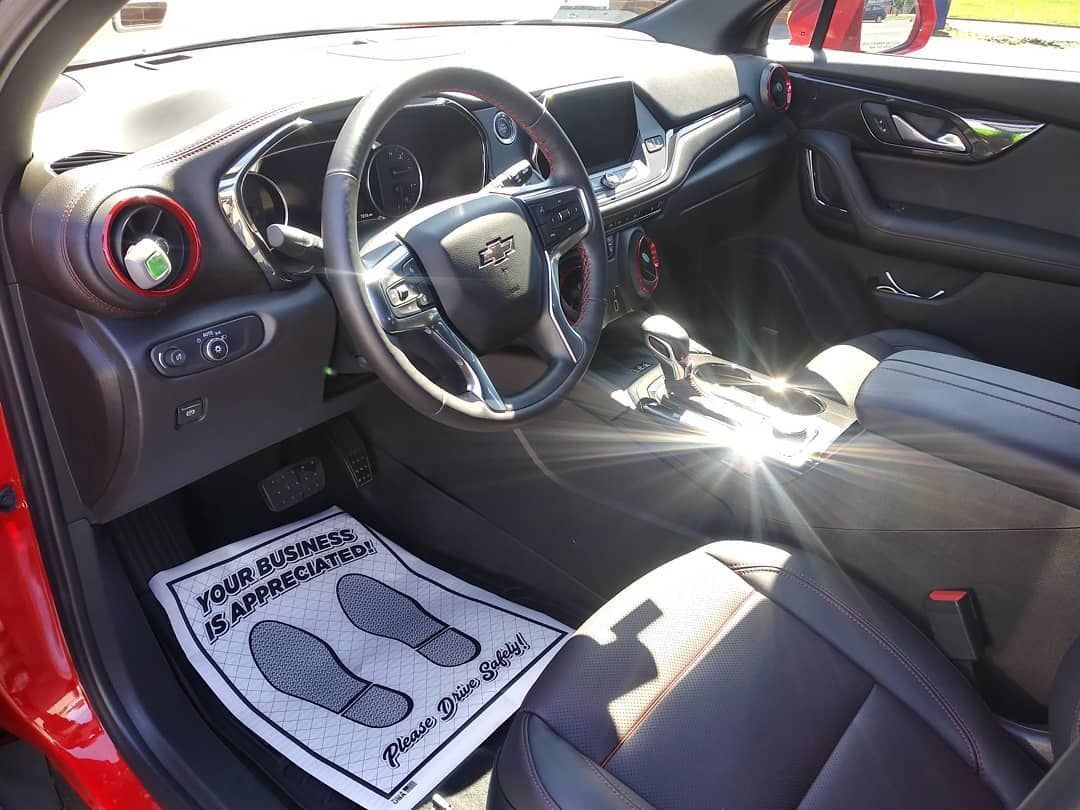 Interior of a red Chevrolet Blazer; steering wheel, dashboard, seats, and floor mat visible.