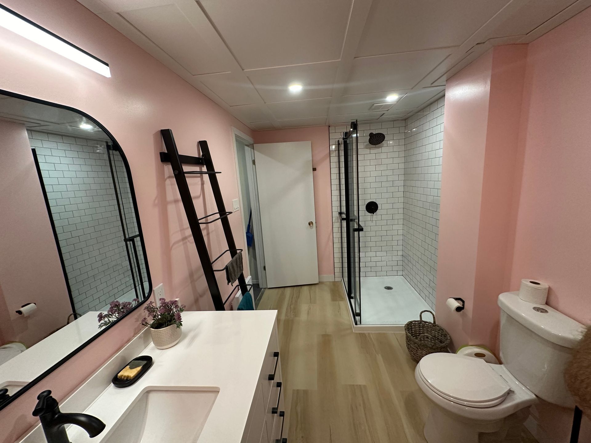 Une salle de bain avec des murs roses, un WC, un lavabo et un miroir.