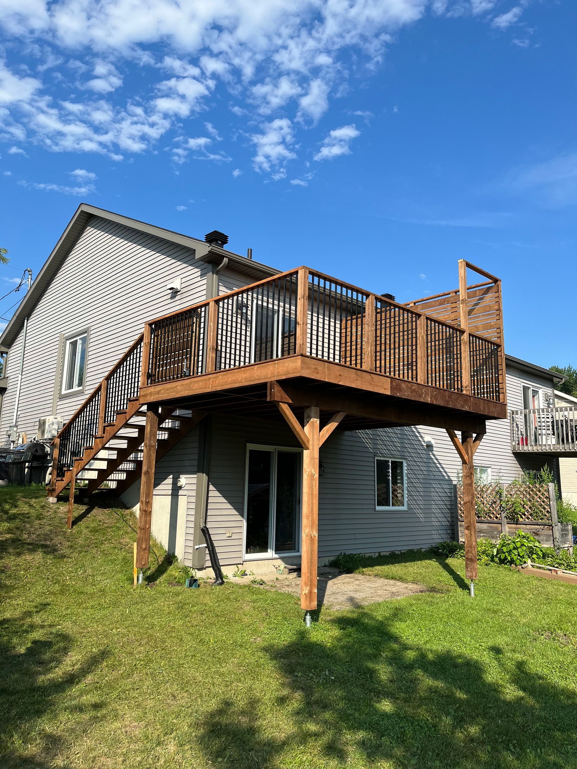 Une grande terrasse en bois avec des escaliers qui y mènent se trouve dans l'arrière-cour d'une maison.