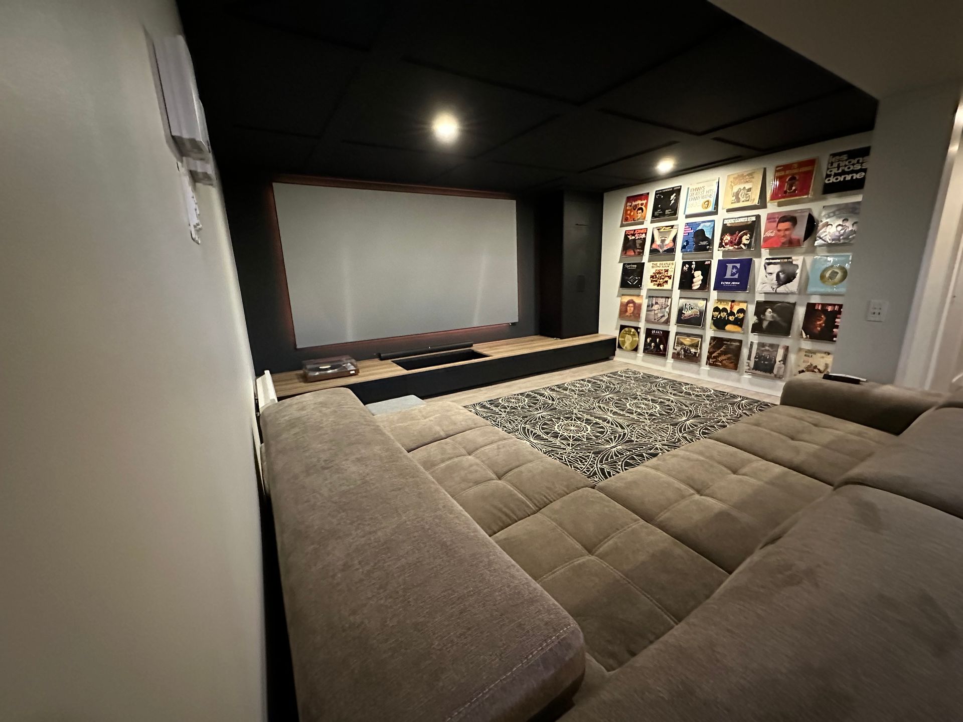 Un salon avec un canapé et un écran de projection.