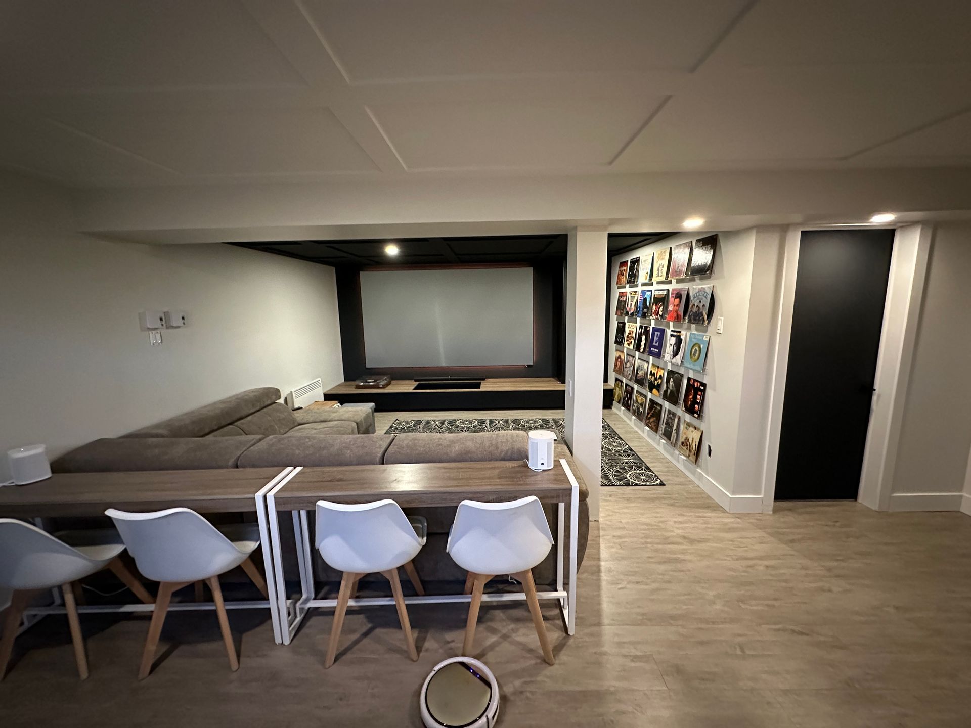 Un salon avec un canapé, une table, des chaises et un écran de projection.