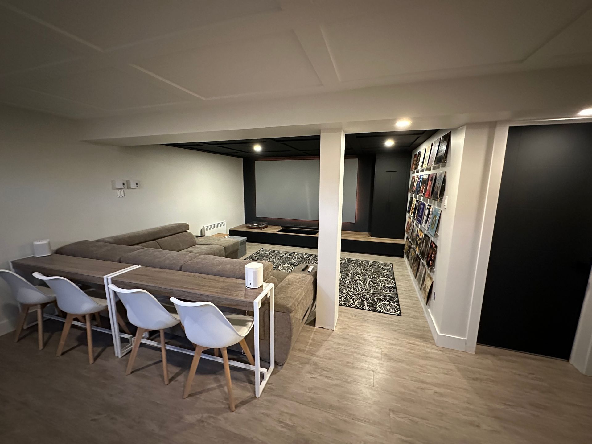 Un salon avec un canapé, une table, des chaises et un écran de projection.