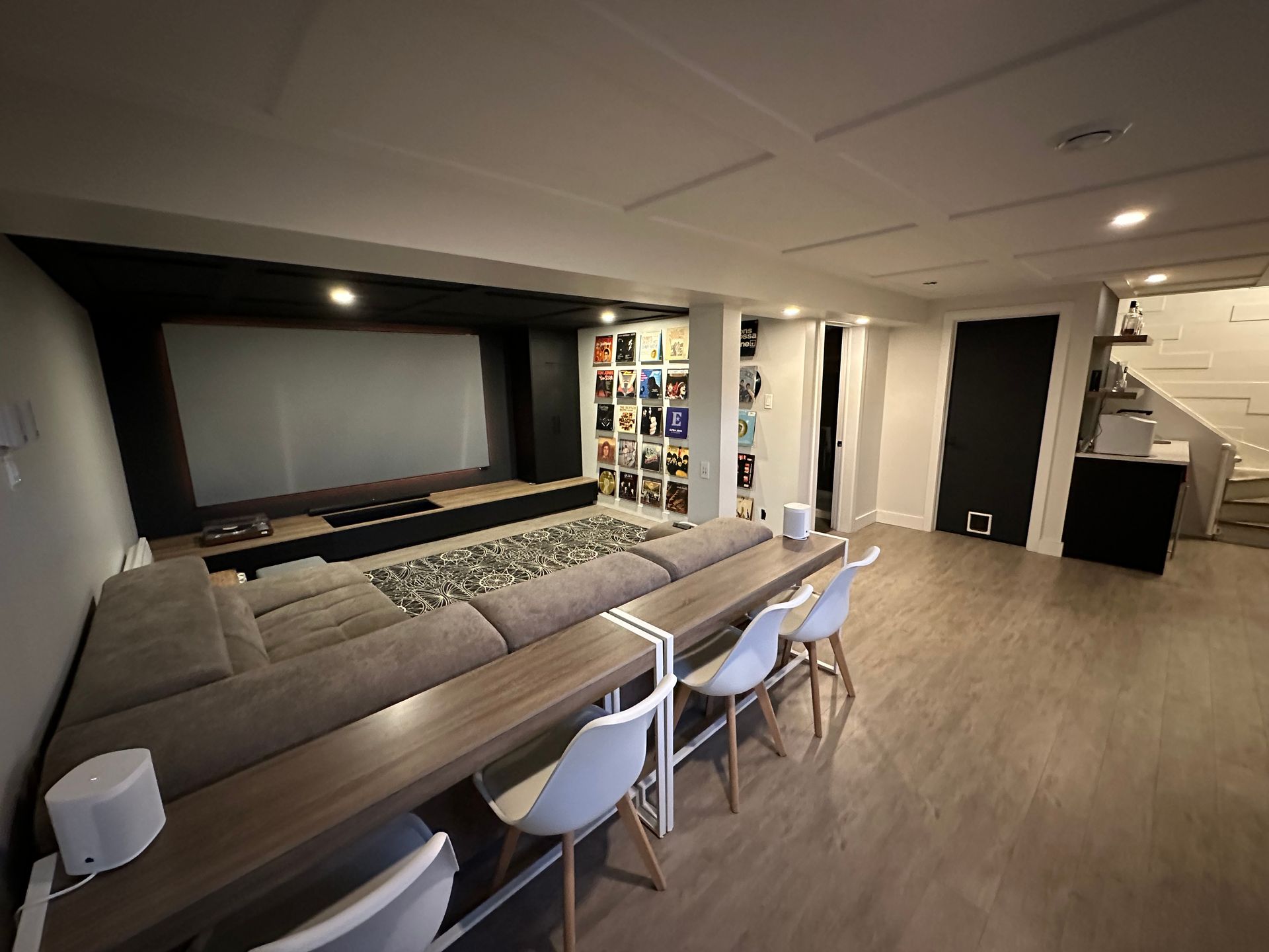 Un salon avec un canapé, une table, des chaises et un écran de projection.