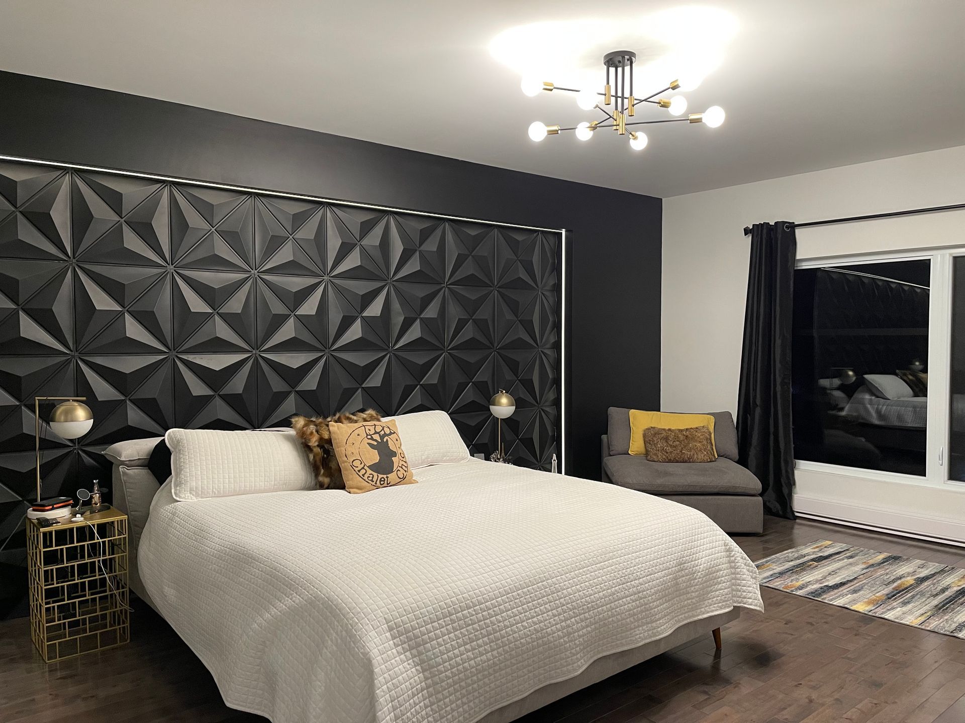 Une chambre avec un lit, une chaise, une table de chevet et un lustre.