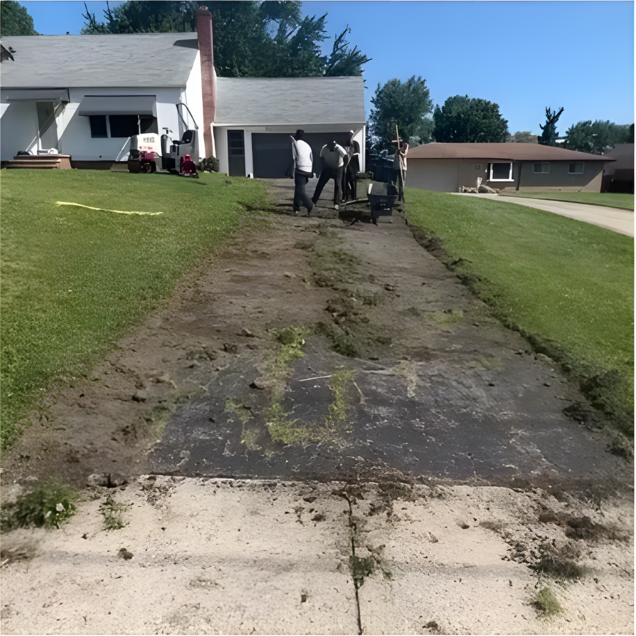 A group of people are working on a driveway in front of a house