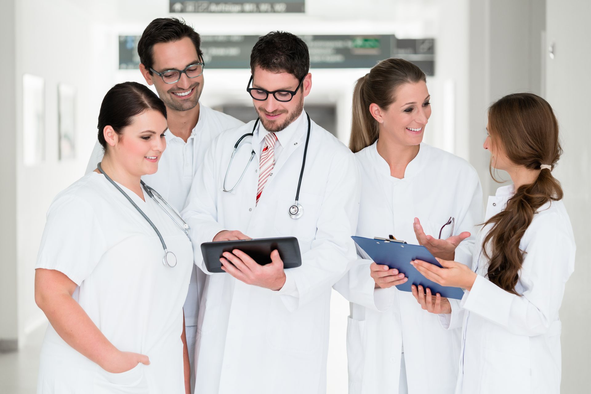 Ein Arzt mit Stethoskop lächelt und legt einem Patienten in einem gut beleuchteten Arztzimmer die Hand auf die Schulter.