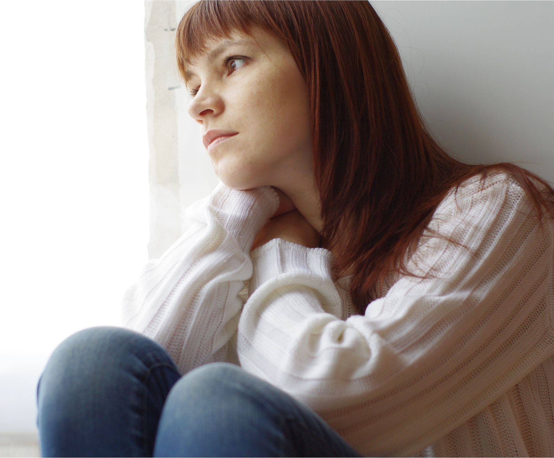Eine Frau sitzt auf dem Boden und schaut aus dem Fenster