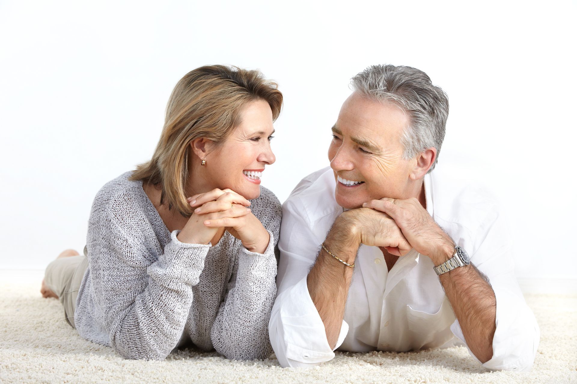 Ein Mann und eine Frau liegen auf dem Boden und lächeln einander an.