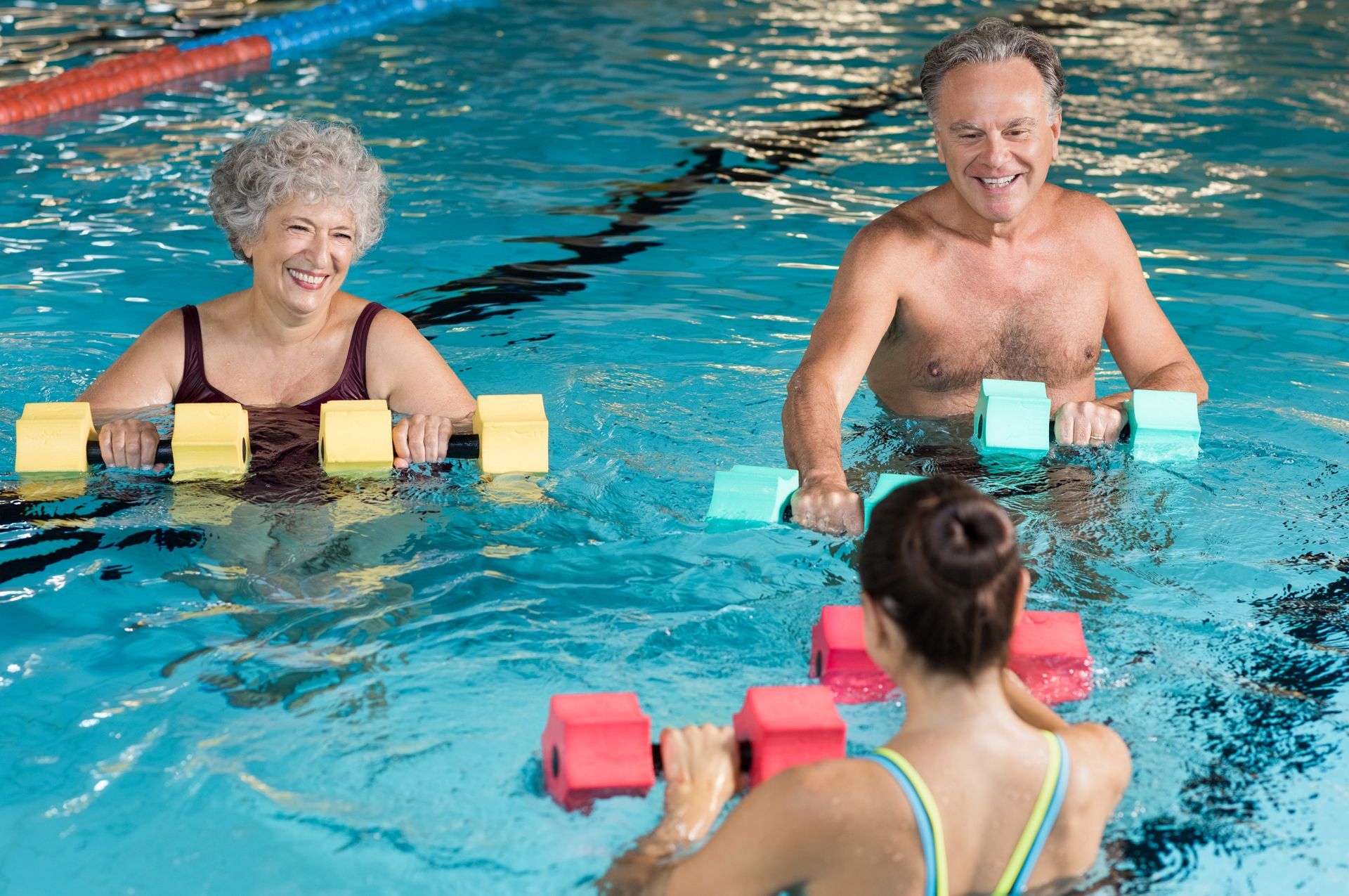 Ein Mann und eine Frau halten Hanteln in einem Schwimmbecken.