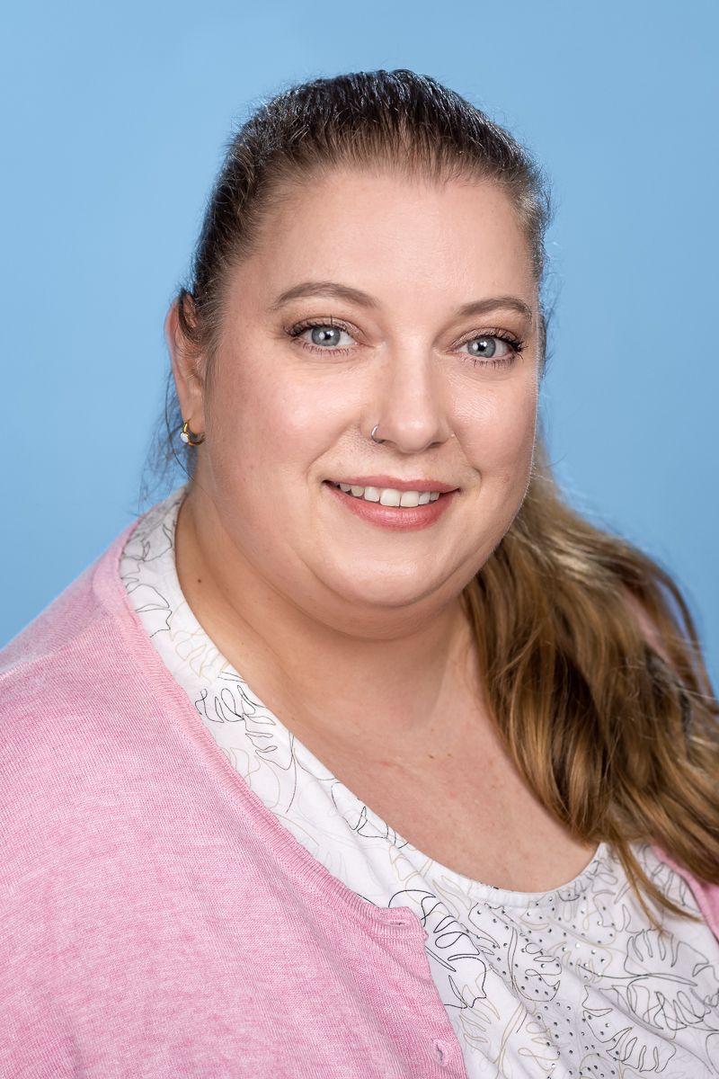 Eine Frau mit Brille und blauem Hemd lächelt in die Kamera.