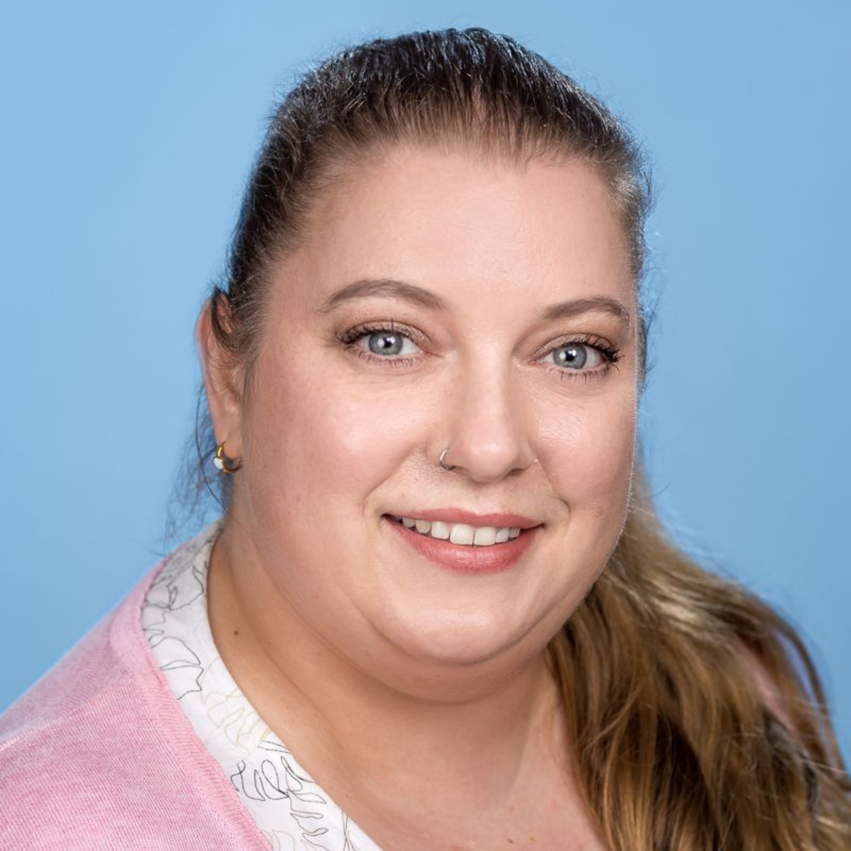 Eine Frau mit Brille und Halskette lächelt in die Kamera.