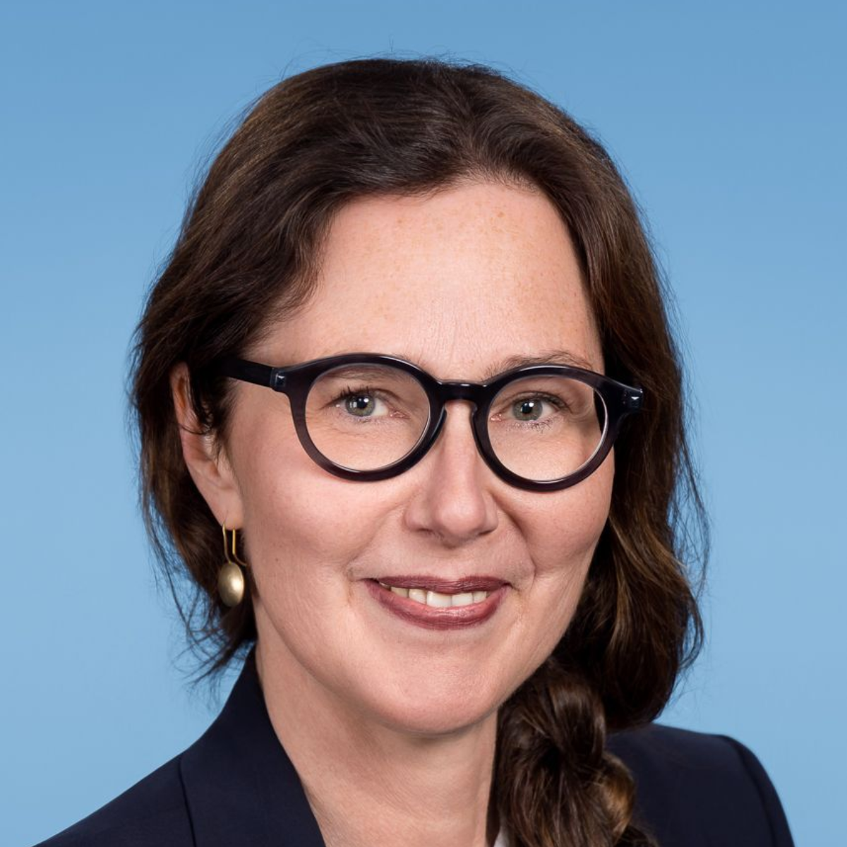 Eine Frau im grünen OP-Kittel lächelt in die Kamera.