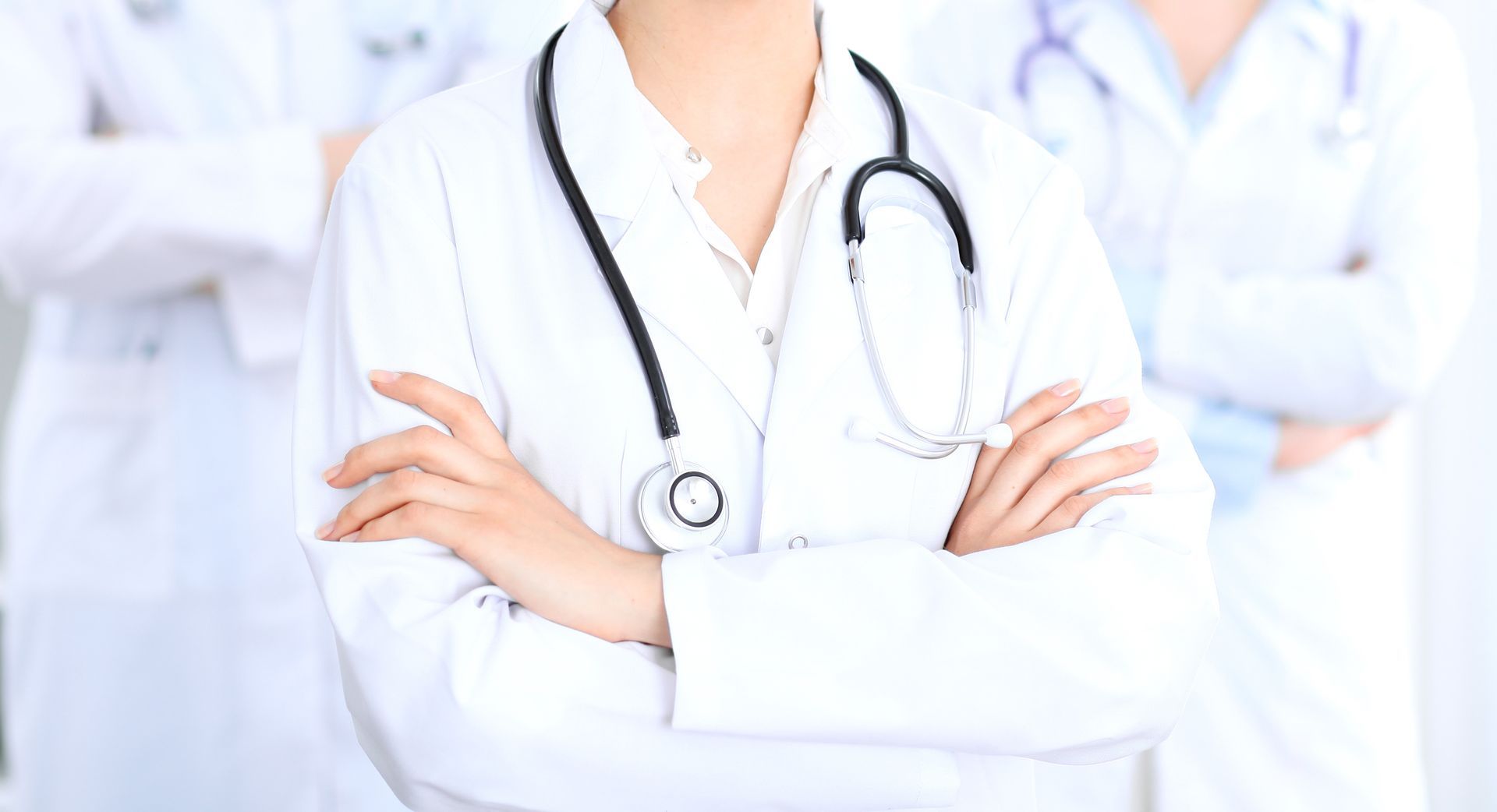 Eine Gruppe von Ärzten steht mit verschränkten Armen nebeneinander.