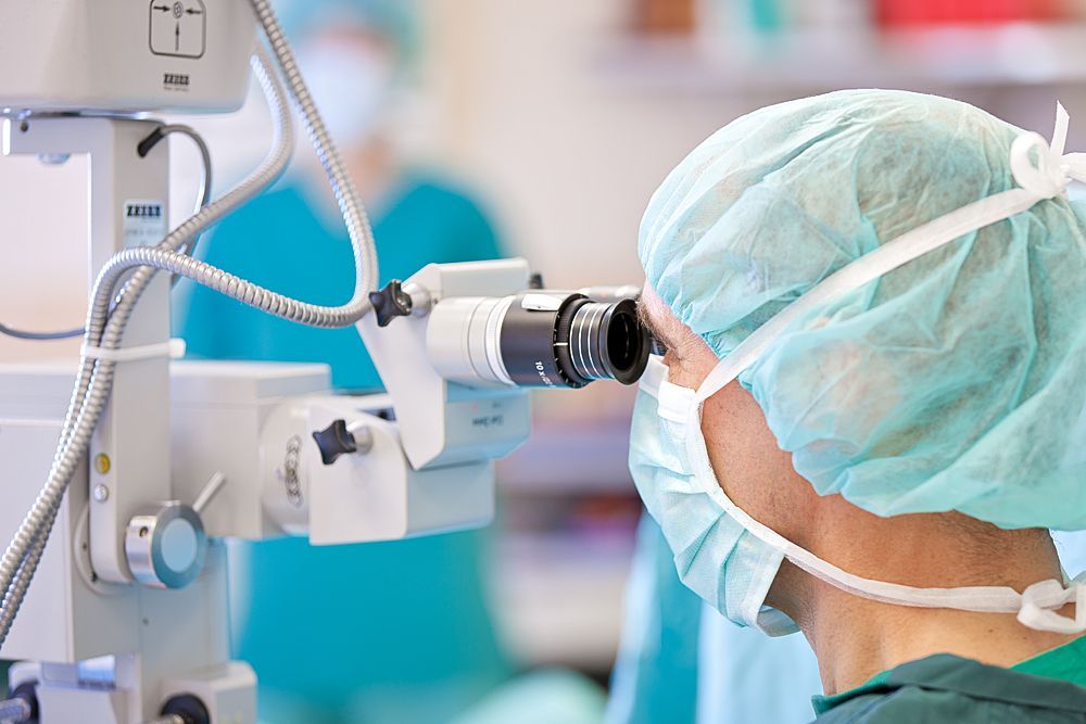 Ein Chirurg schaut in einem Operationssaal durch ein Mikroskop.